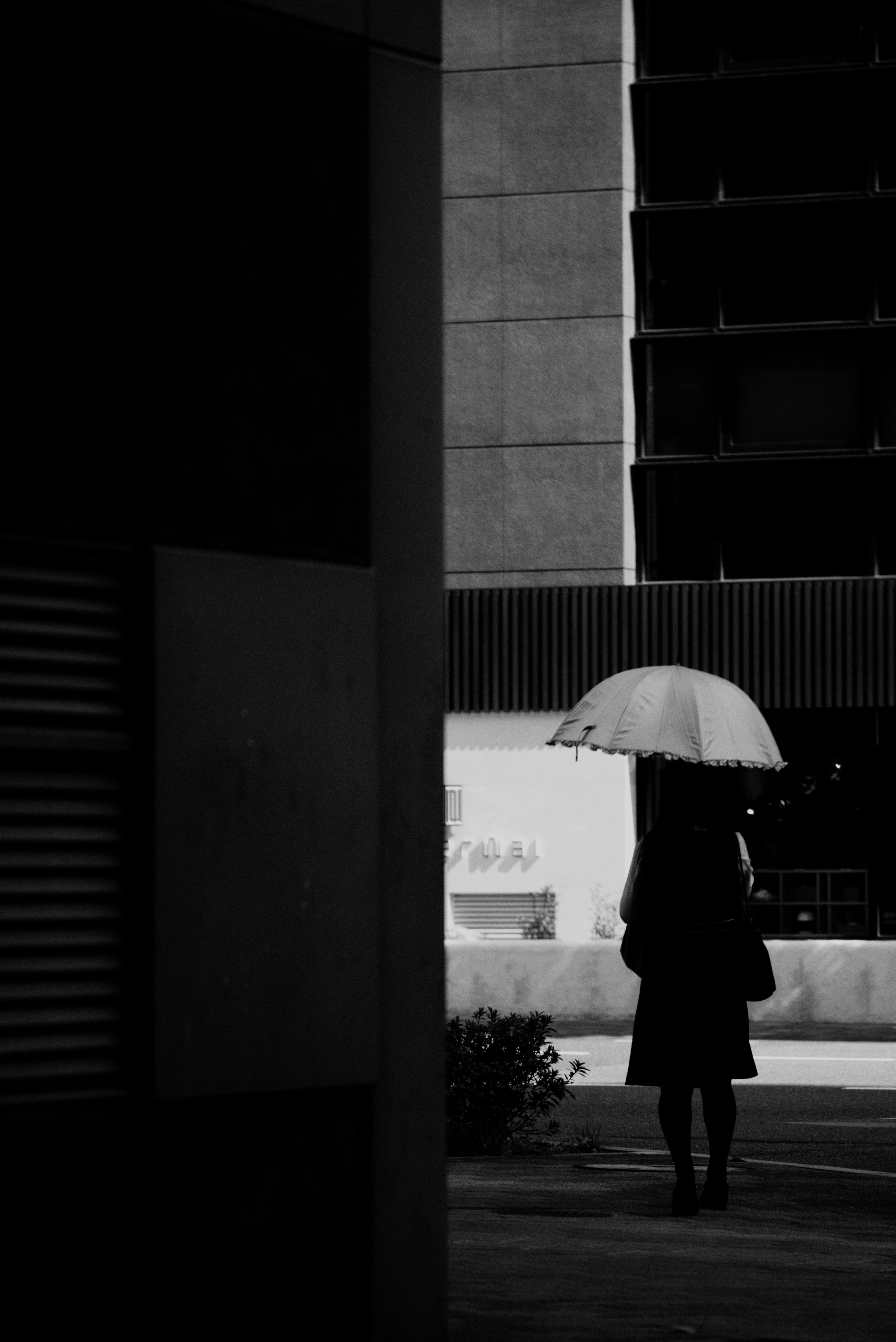 Eine Frau mit einem Regenschirm, die in einer monochromen städtischen Umgebung geht