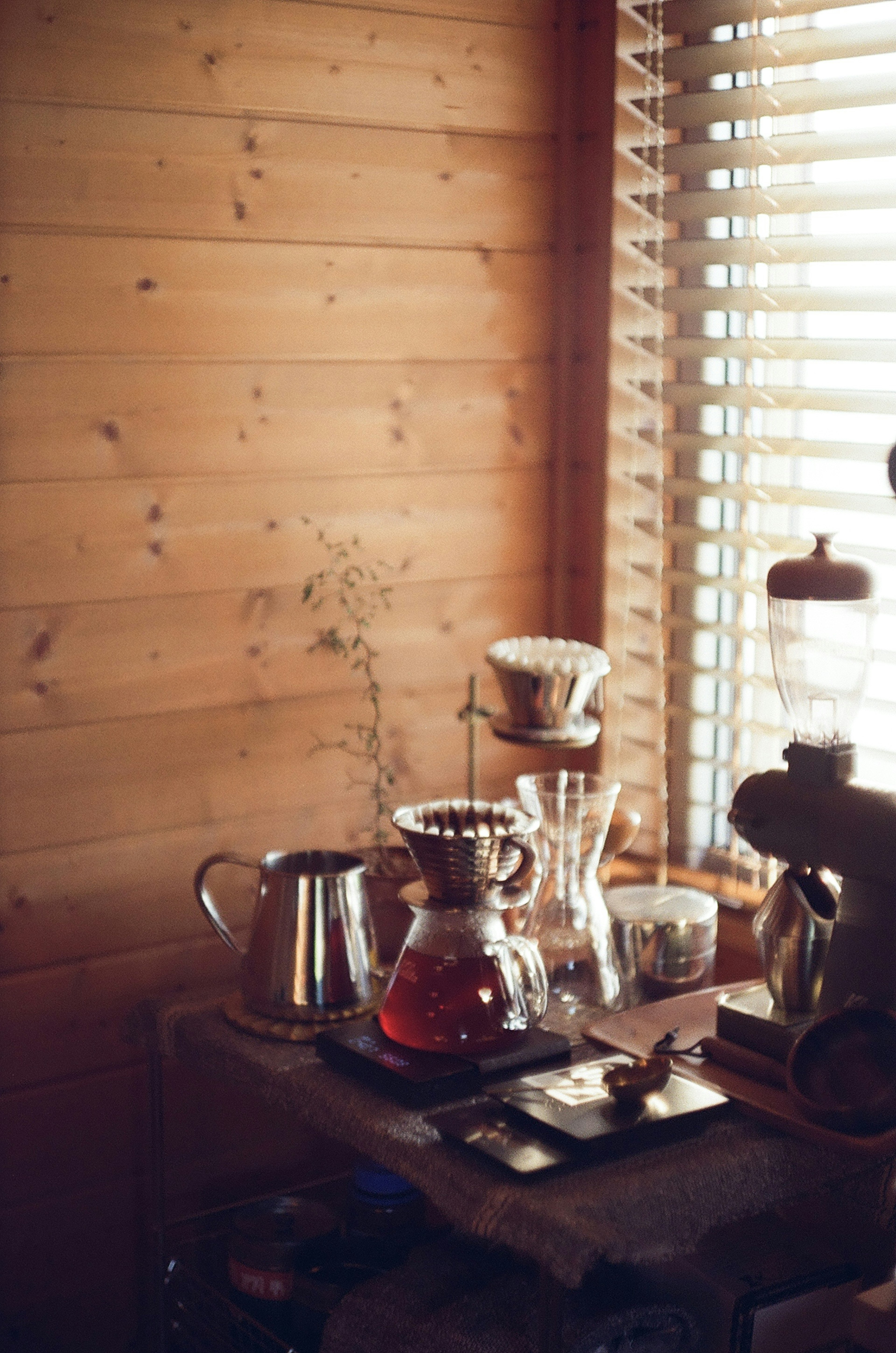 Coffee brewing equipment arranged on a wooden table near a window