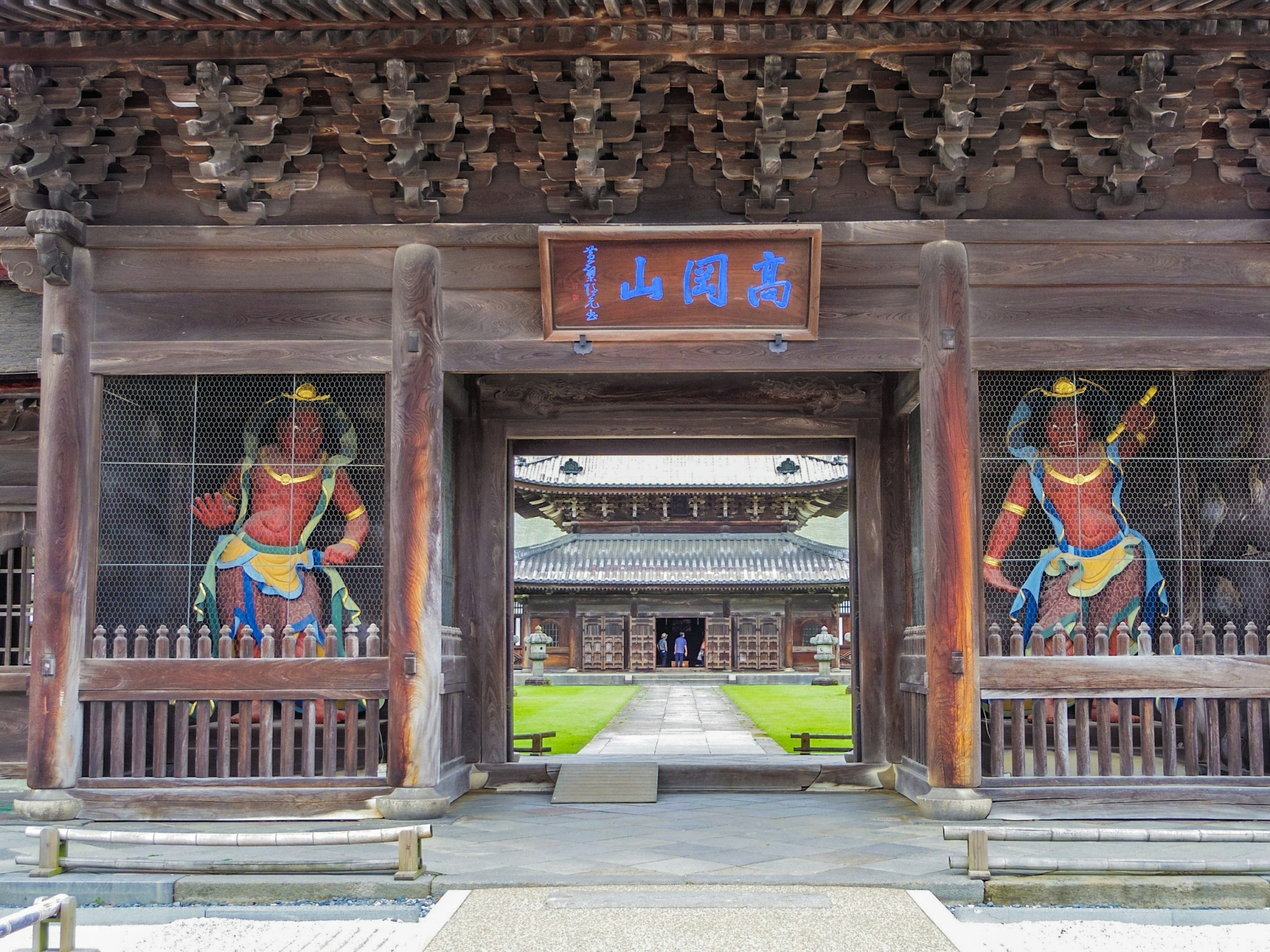 Wooden gate featuring two guardian figures painted on the door