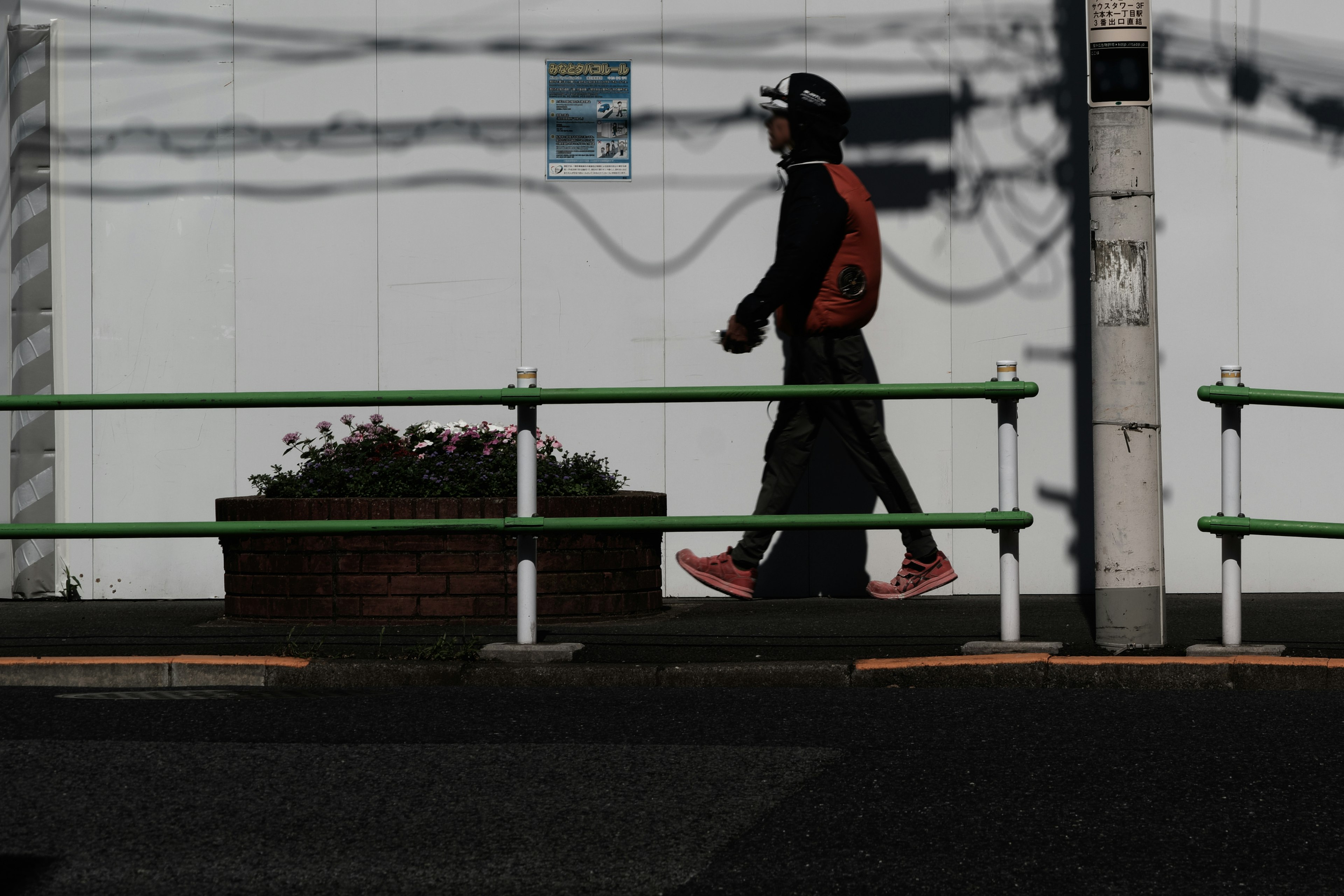 Silhouette of a person walking against a dark background with green railing