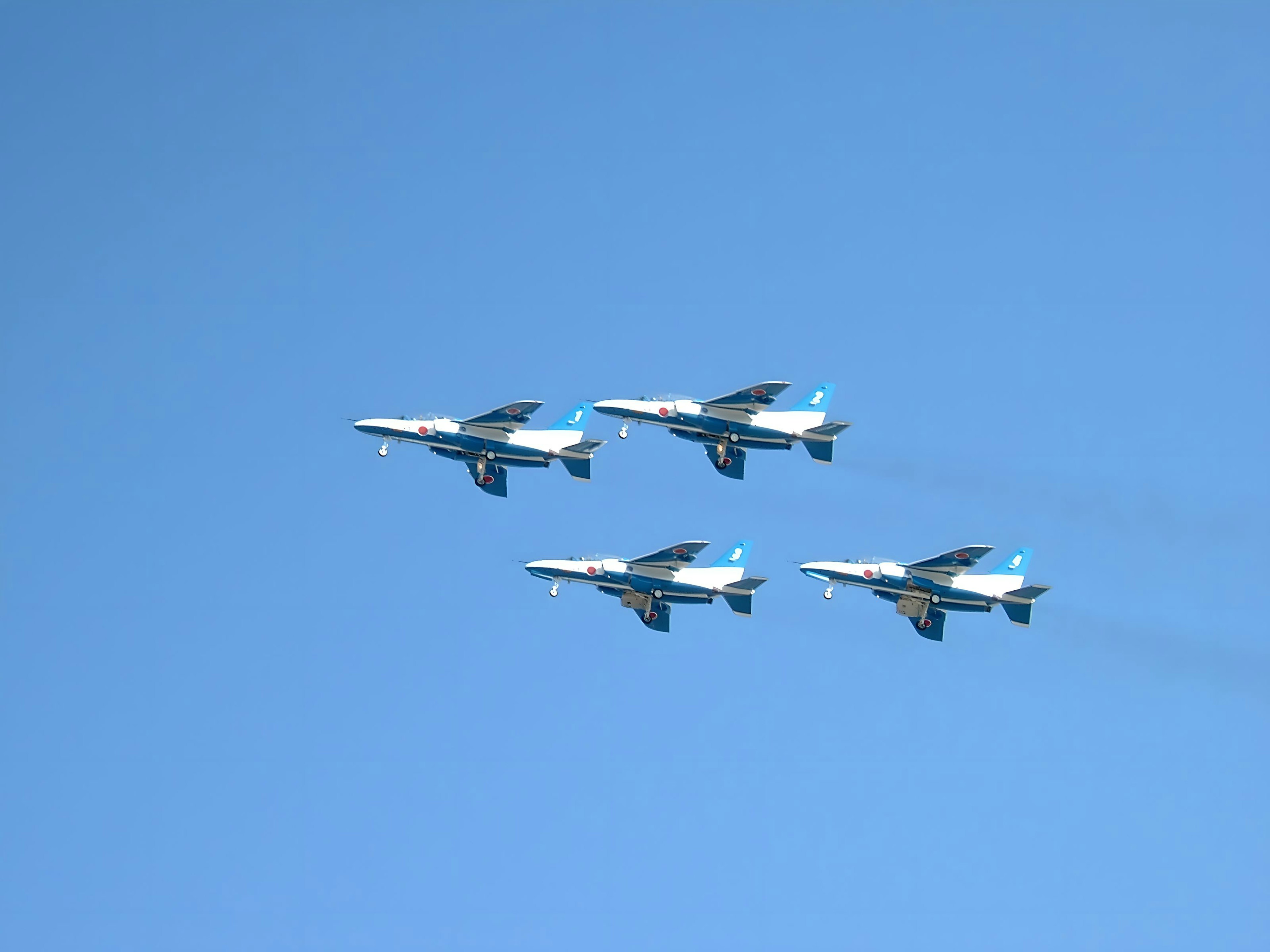 Formation flight of four fighter jets against a blue sky