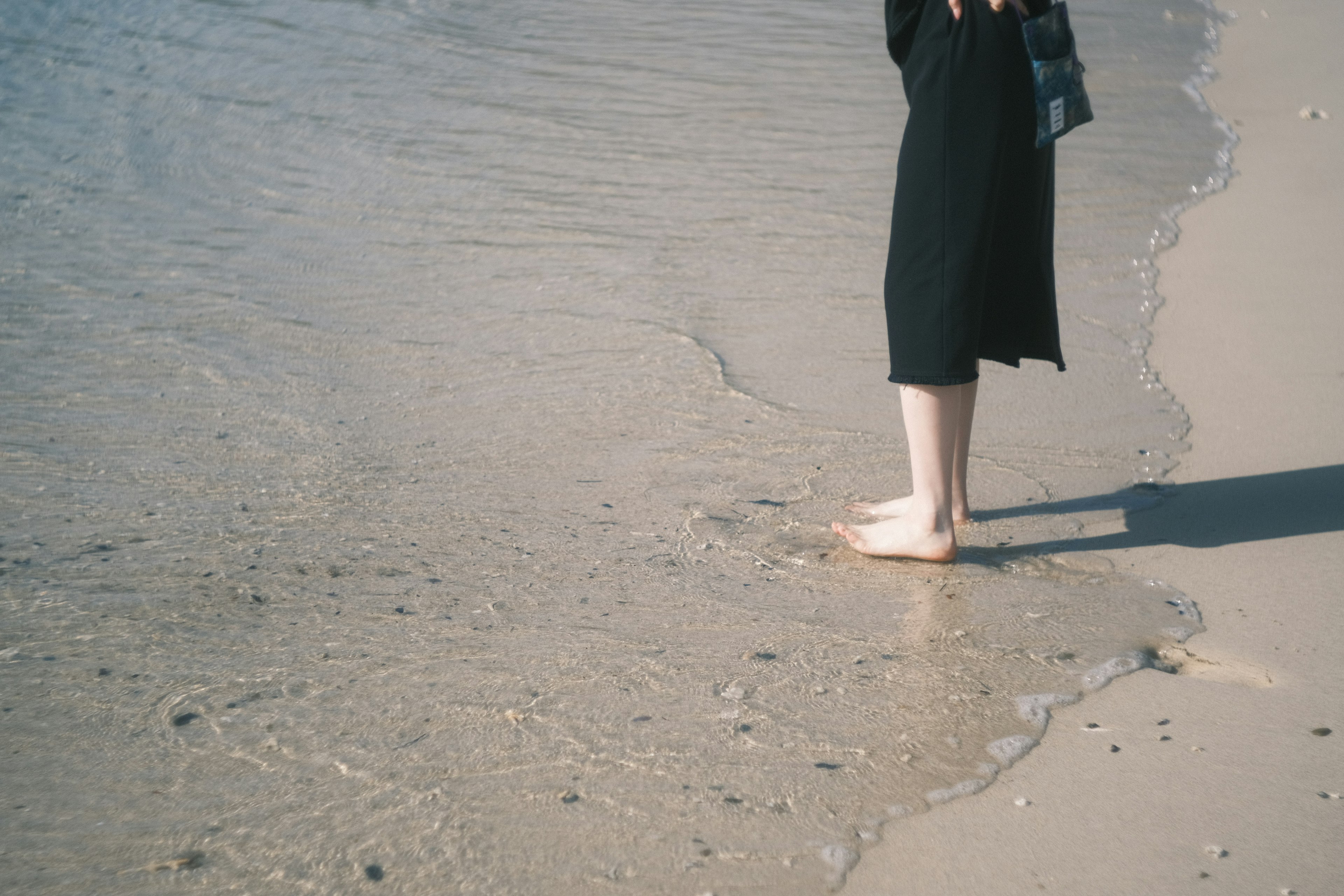 ビーチで水に足を浸している人の足元