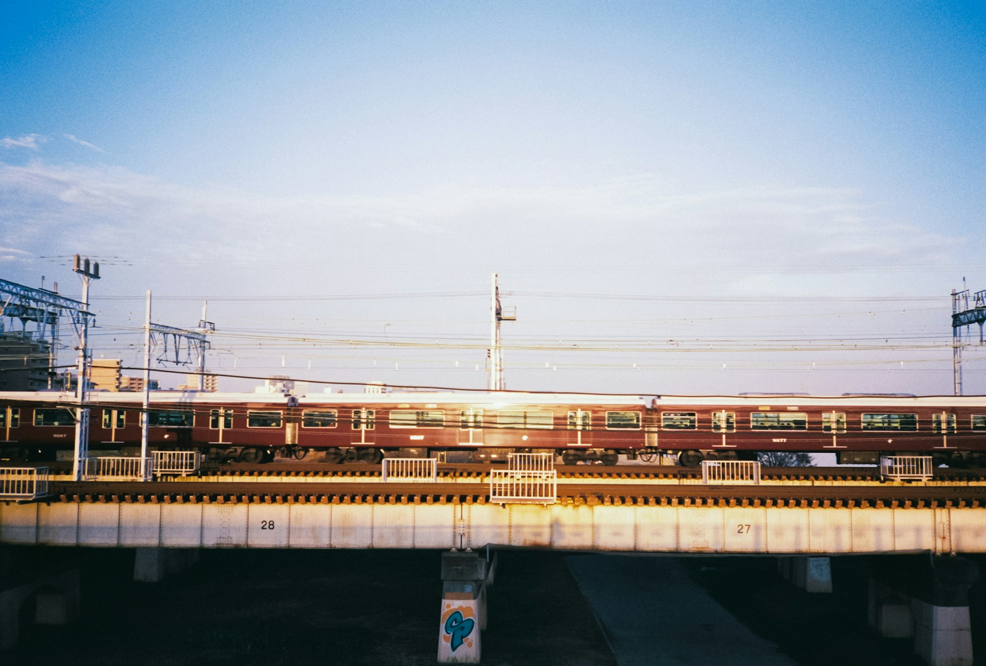 Train passing under a bright sky during sunset