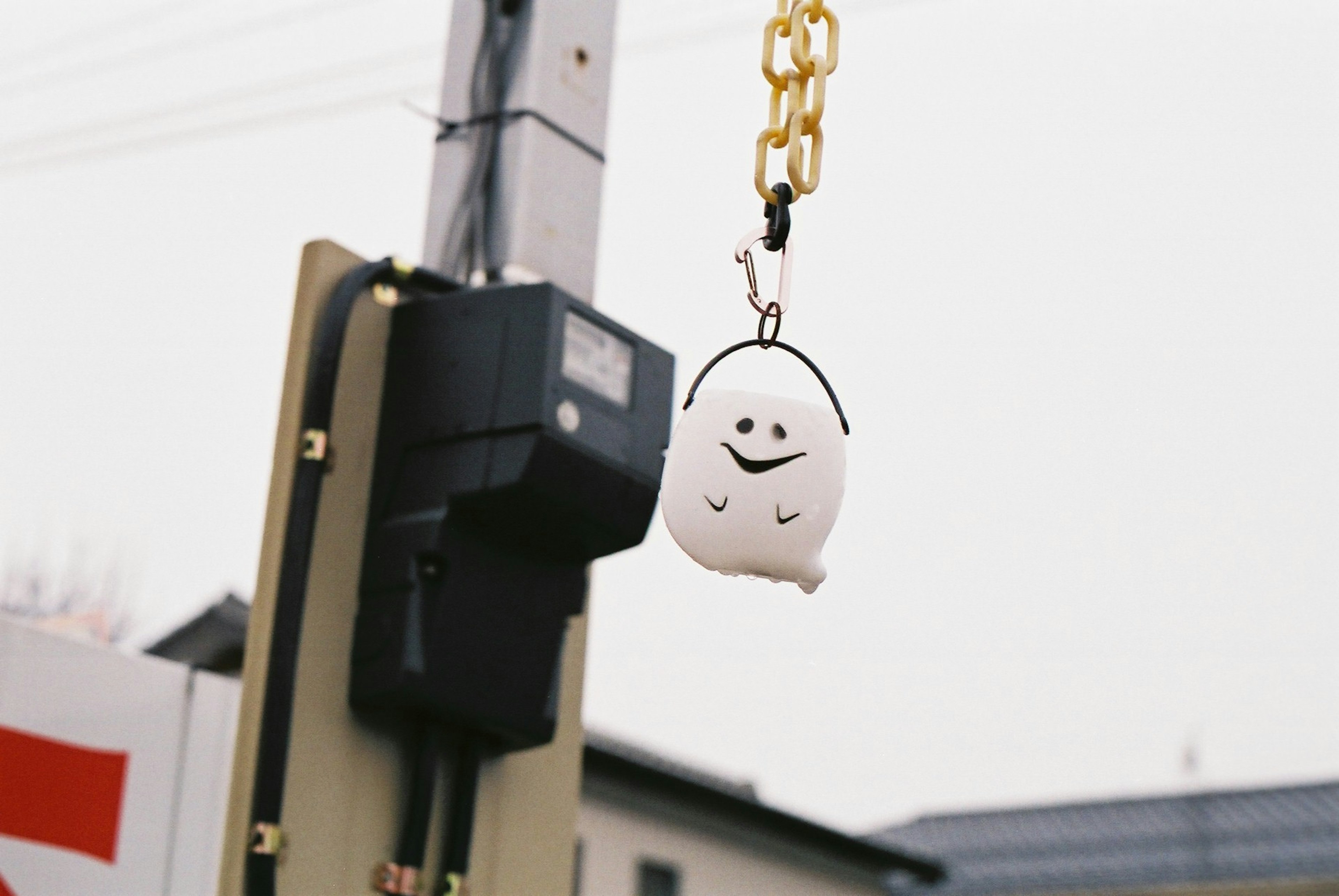 A white character keychain hanging from a gold chain