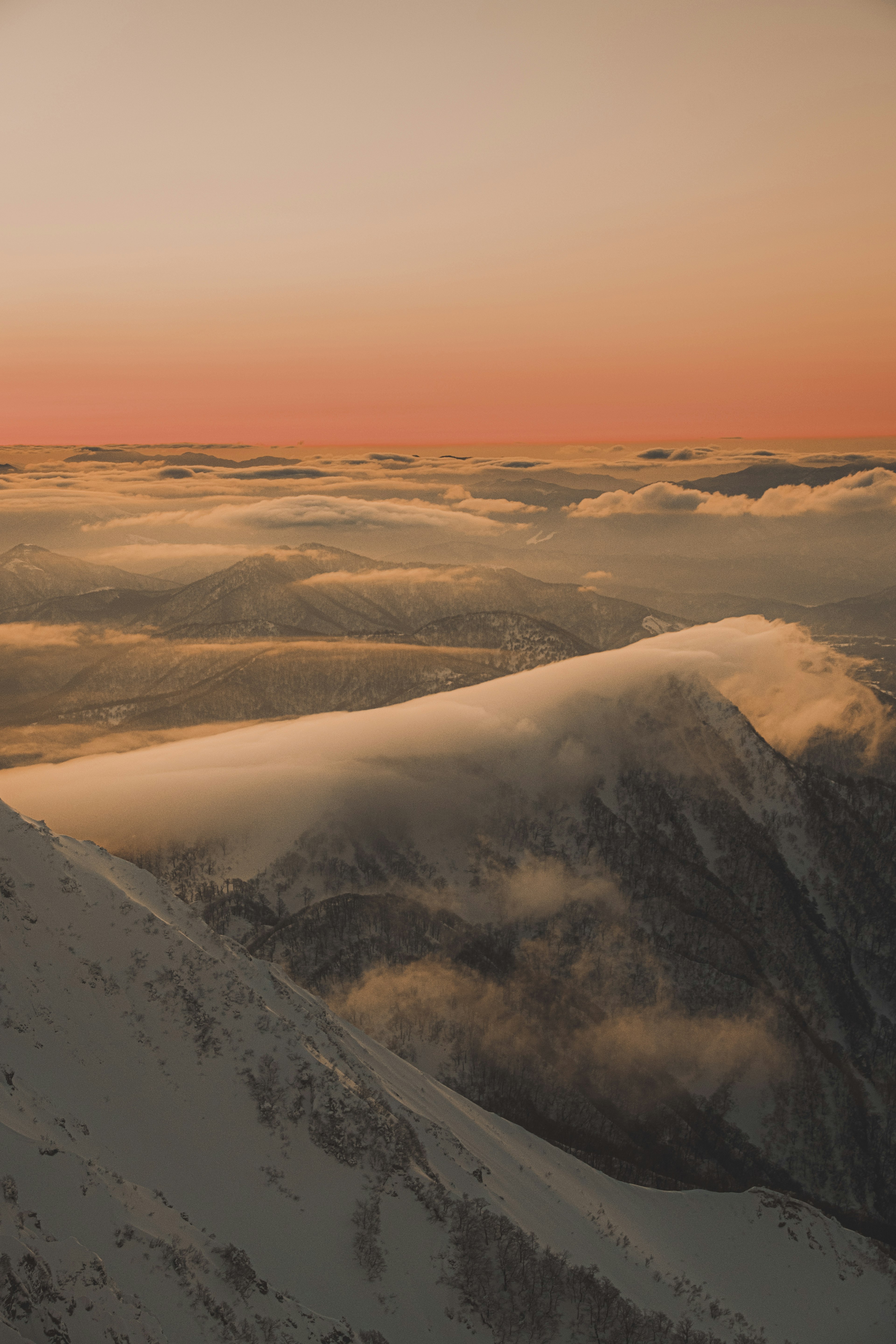 Verschneite Berge mit Wolken unter einem Sonnenuntergangshimmel