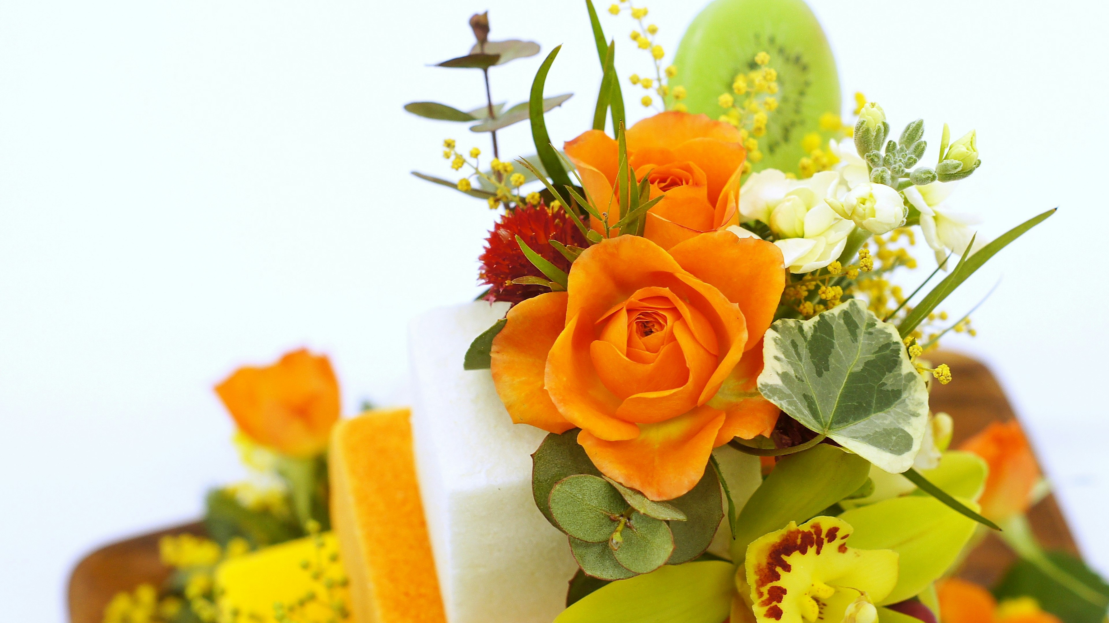 Blumenarrangement mit orangefarbenen Rosen und verschiedenen bunten Blumen