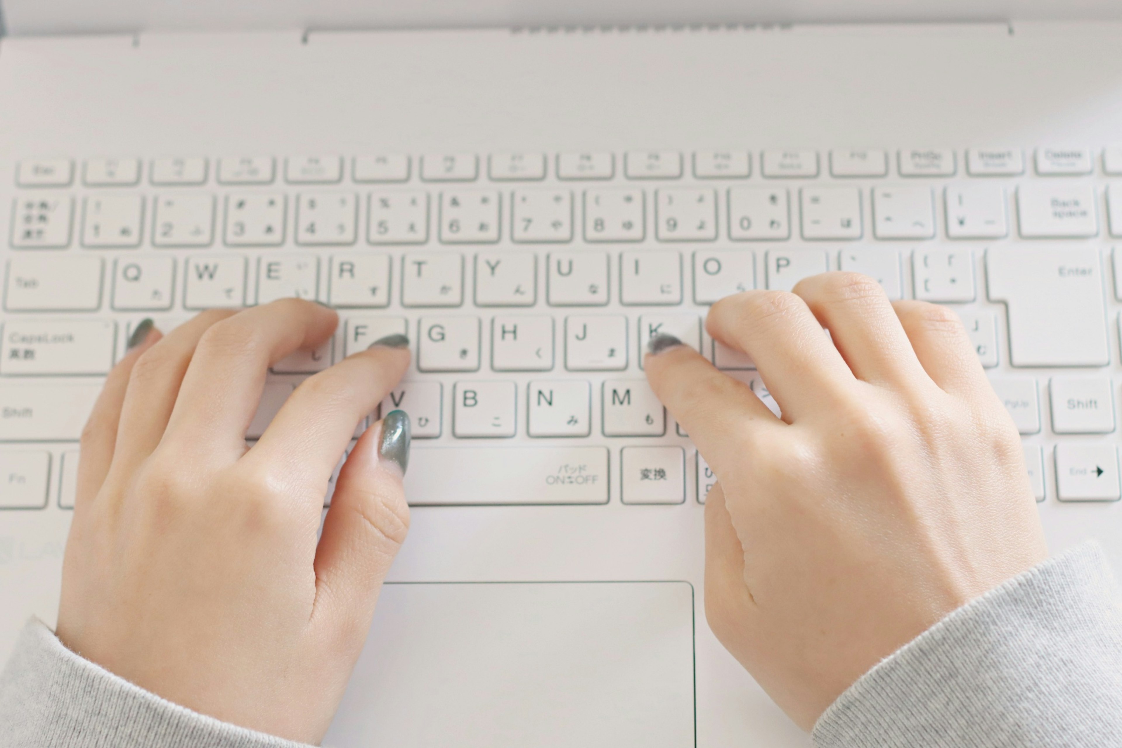 Hands typing on a white laptop keyboard