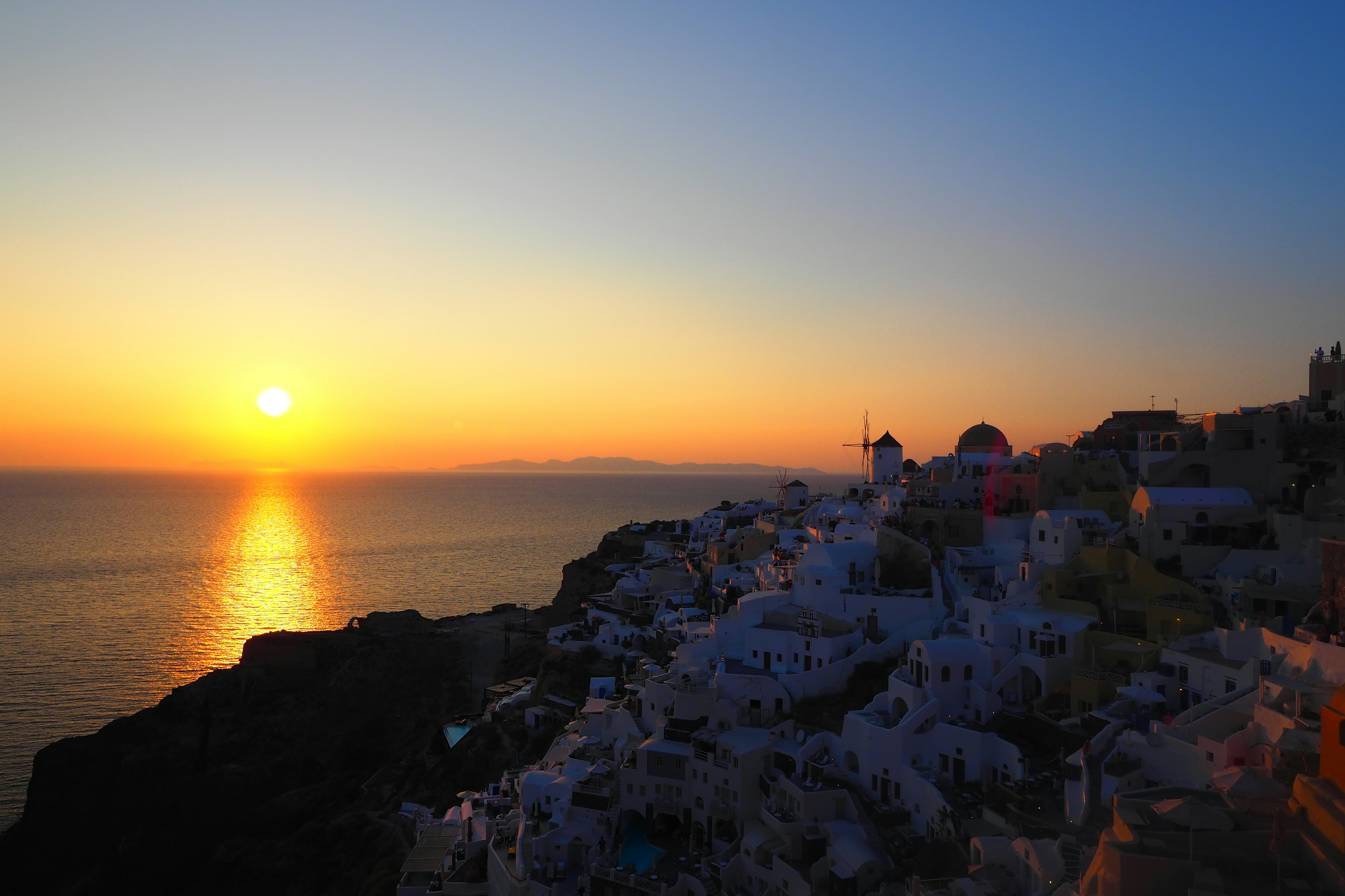 Pemandangan matahari terbenam yang menakjubkan di Santorini bangunan putih di lereng bukit