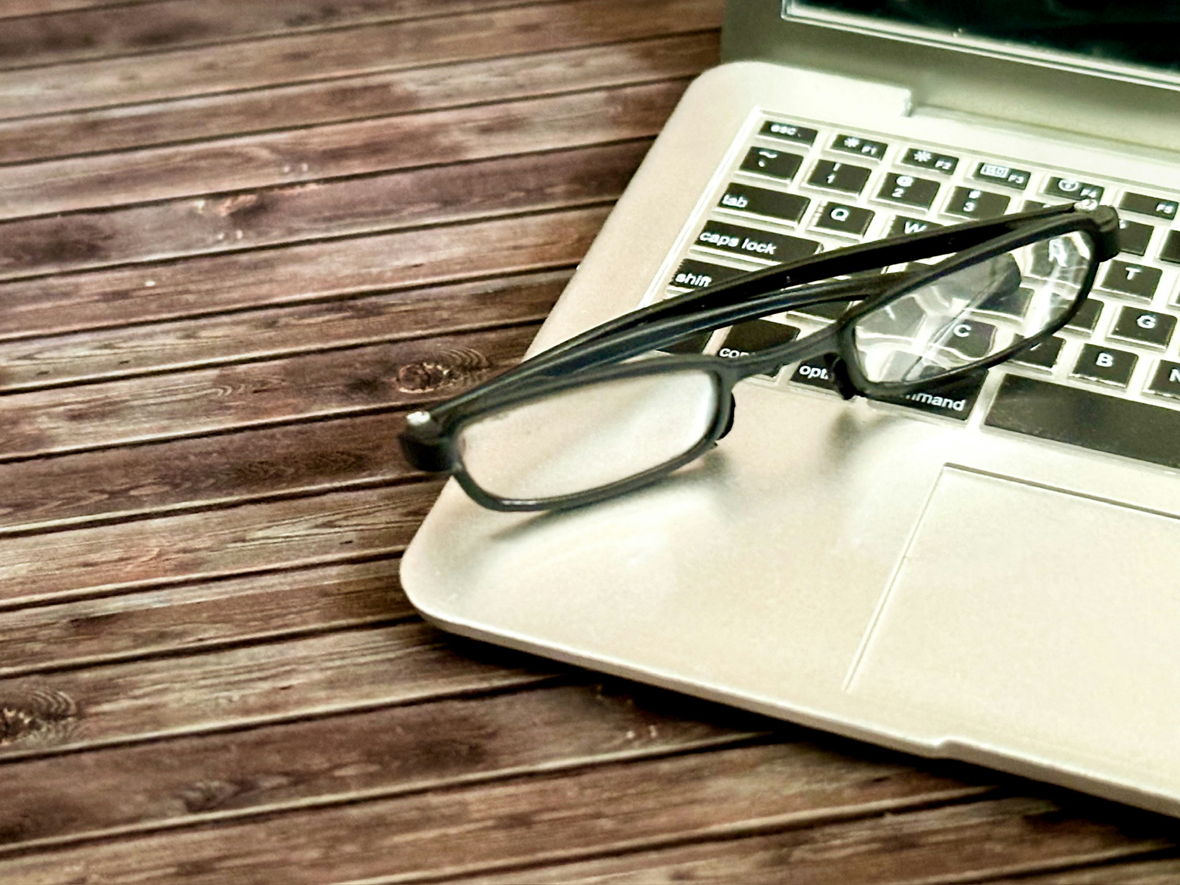 Laptop mit Brille auf einem Holztisch