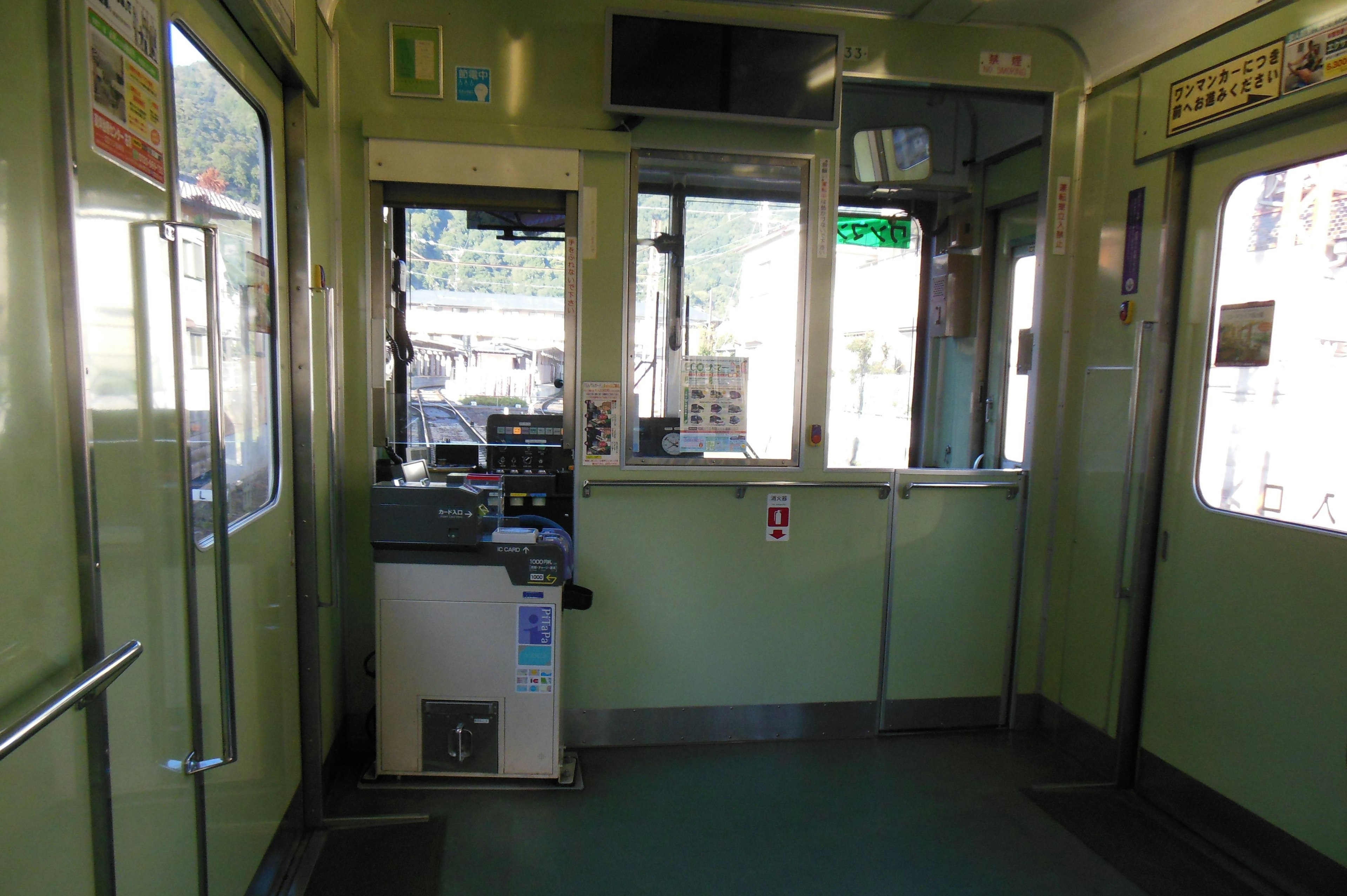 Vista interior de un vagón de tren verde que muestra el área del conductor