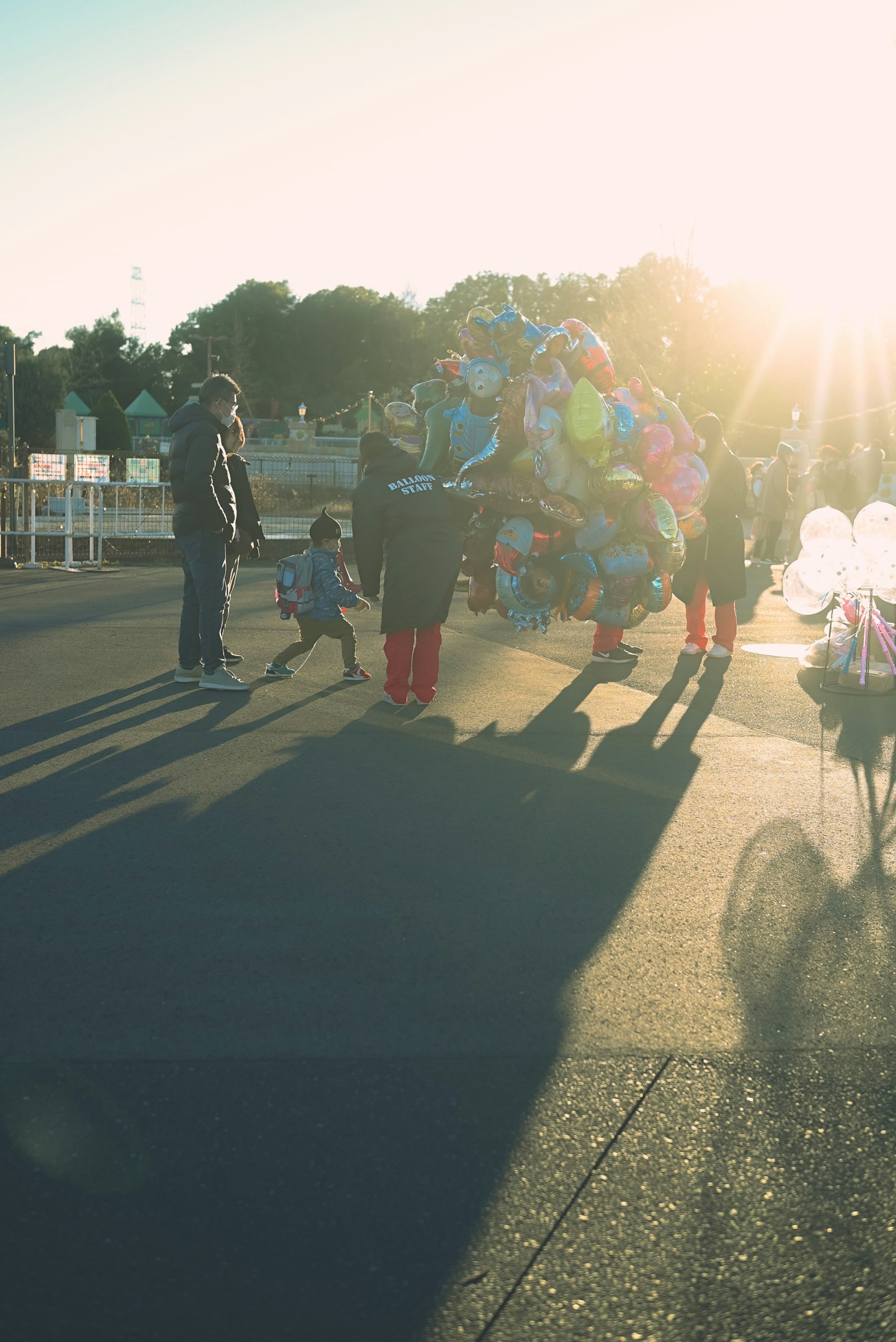 夕日を背にしたバルーン販売者と子供たちの賑やかな風景