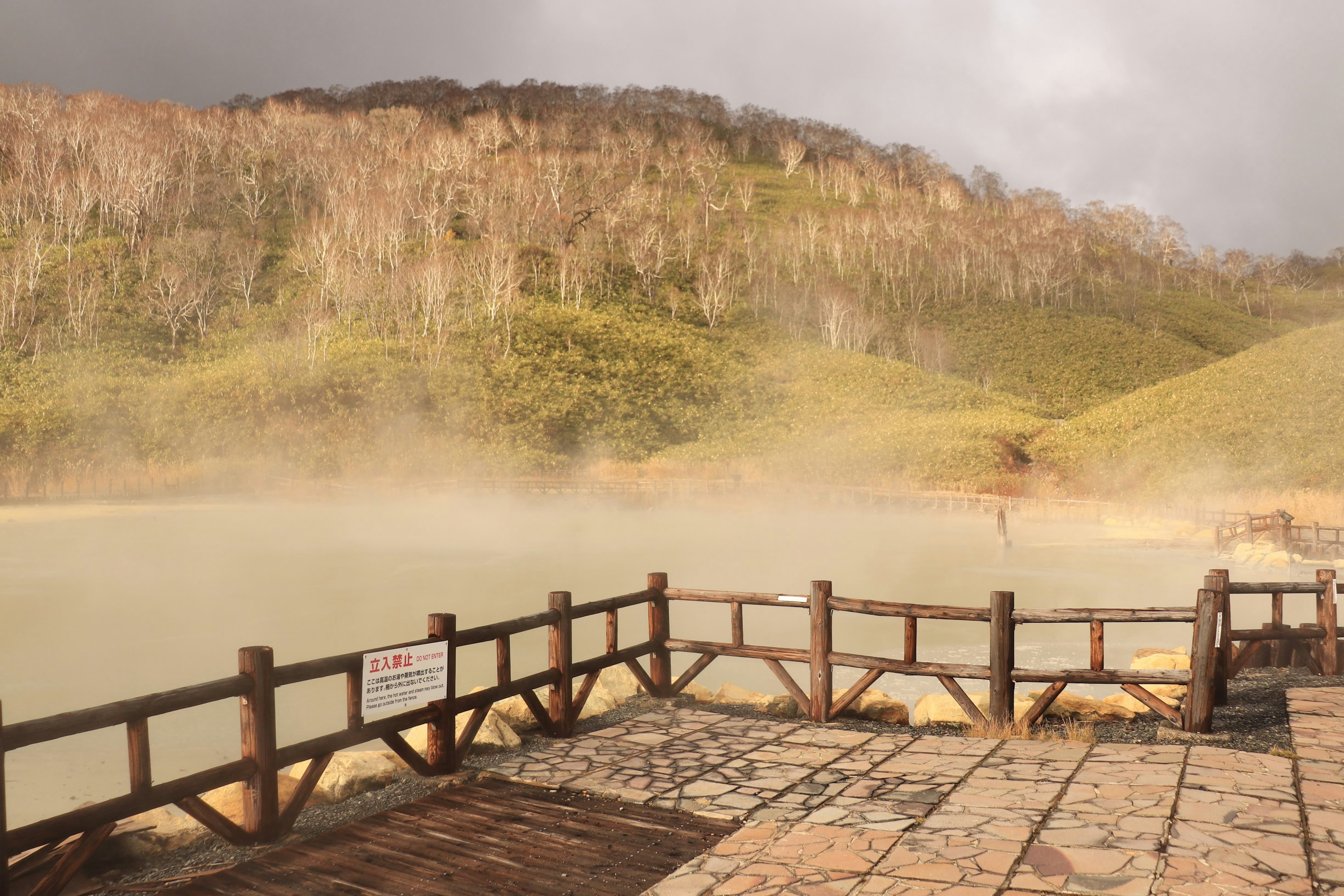 Scenic view of a hot spring with misty mountains