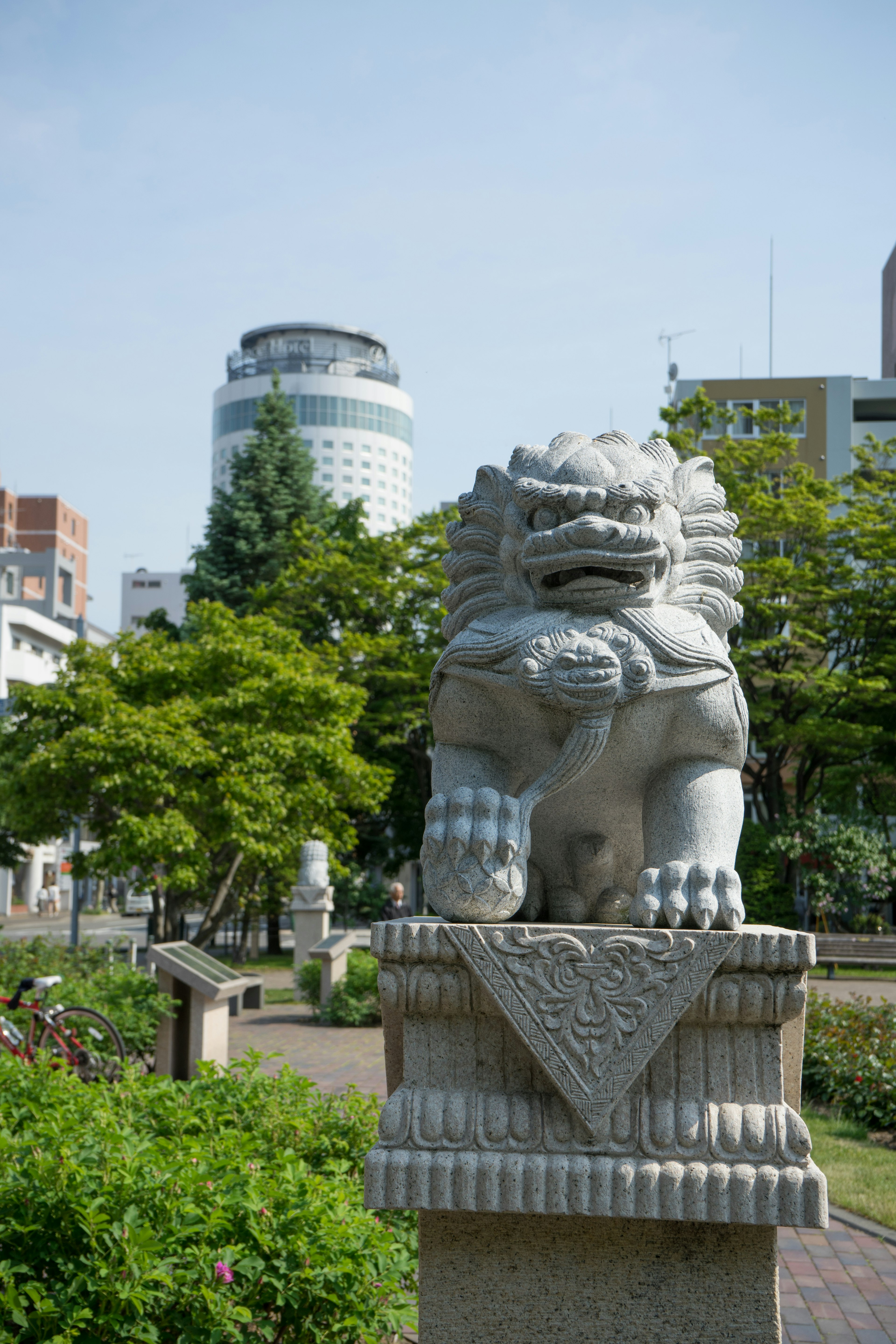 公園にある石の獅子像と背景に現代的なビル