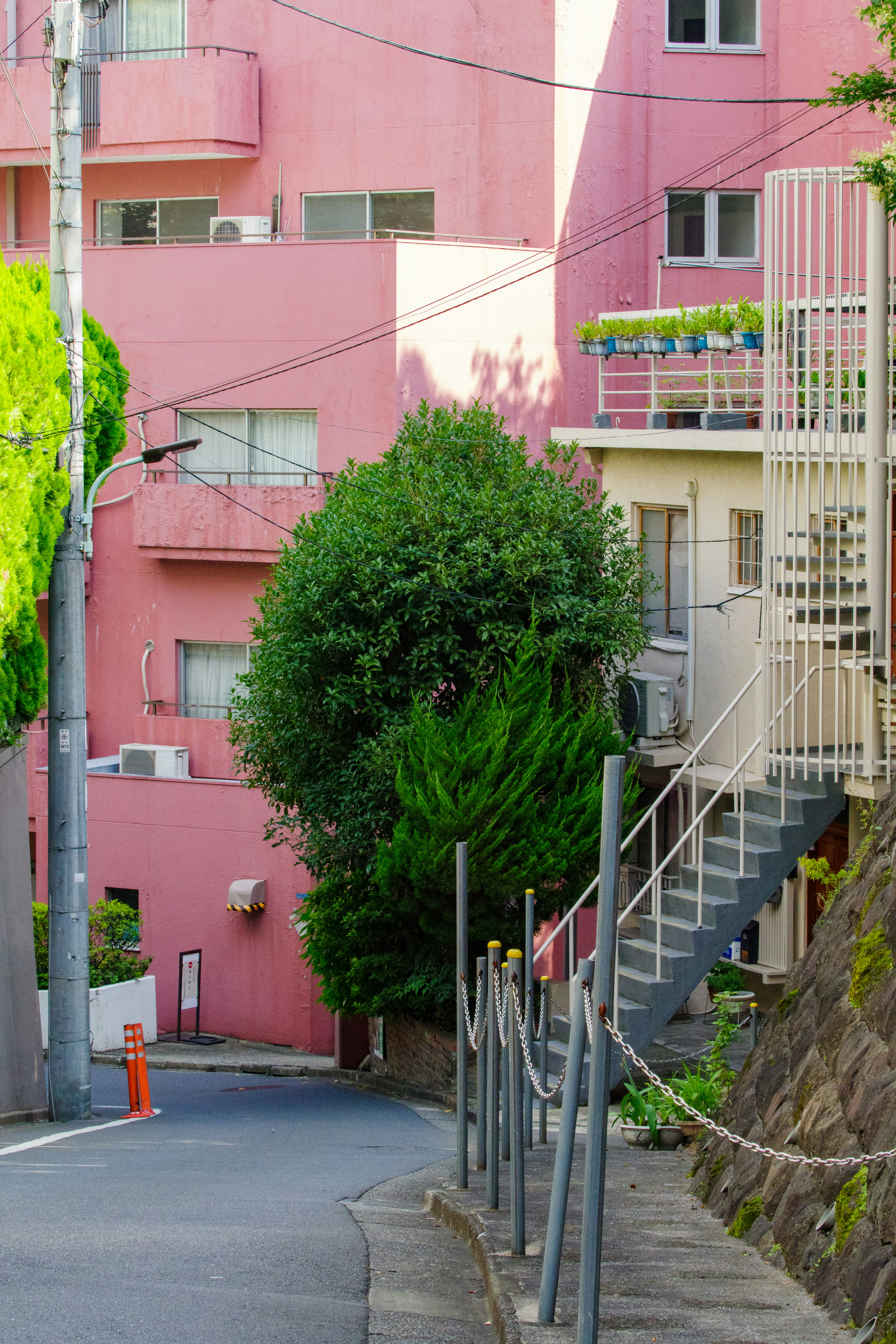 Enge Straßenszene mit rosa Gebäuden und grünen Bäumen