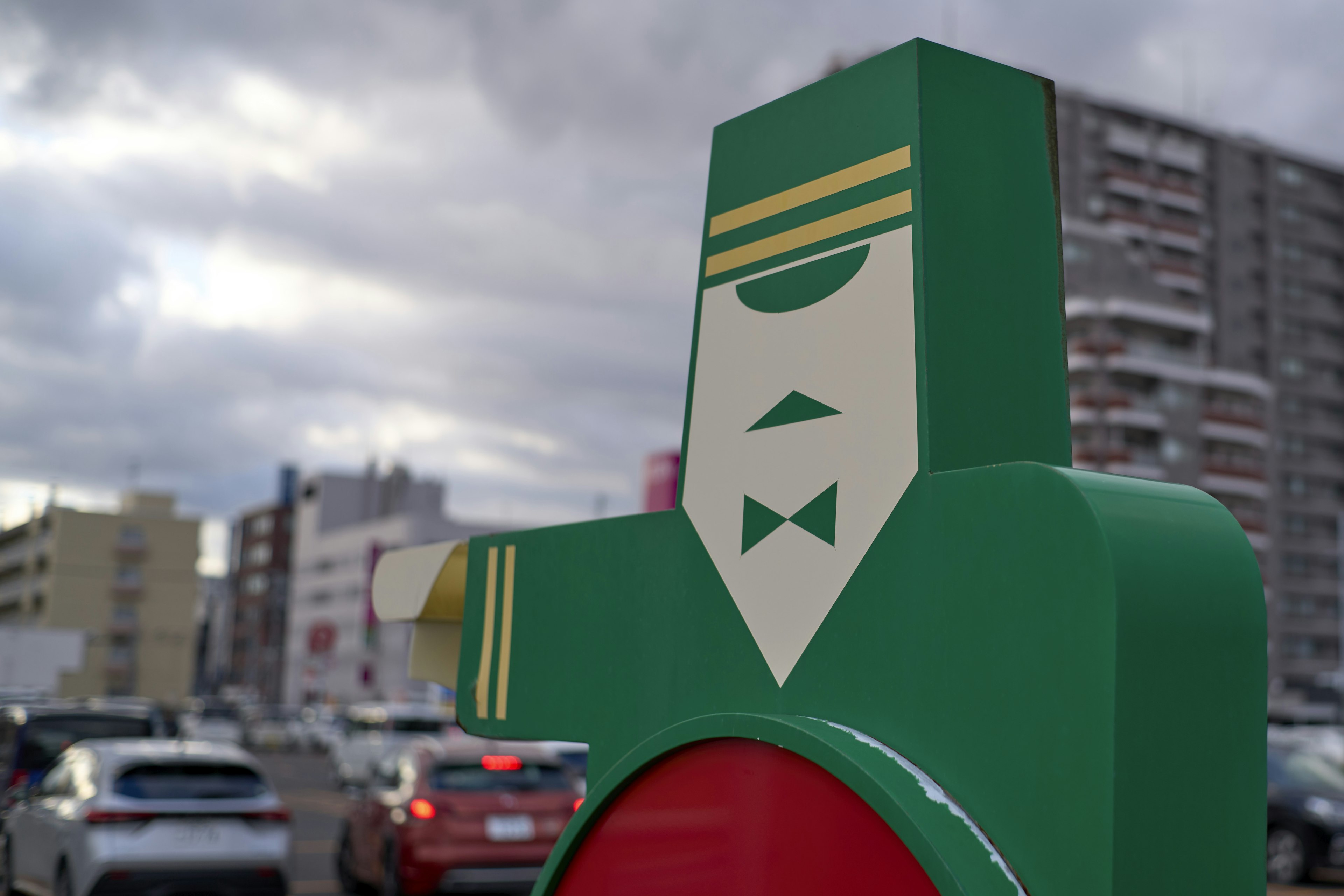 Green traffic light character sculpture with a cityscape backdrop