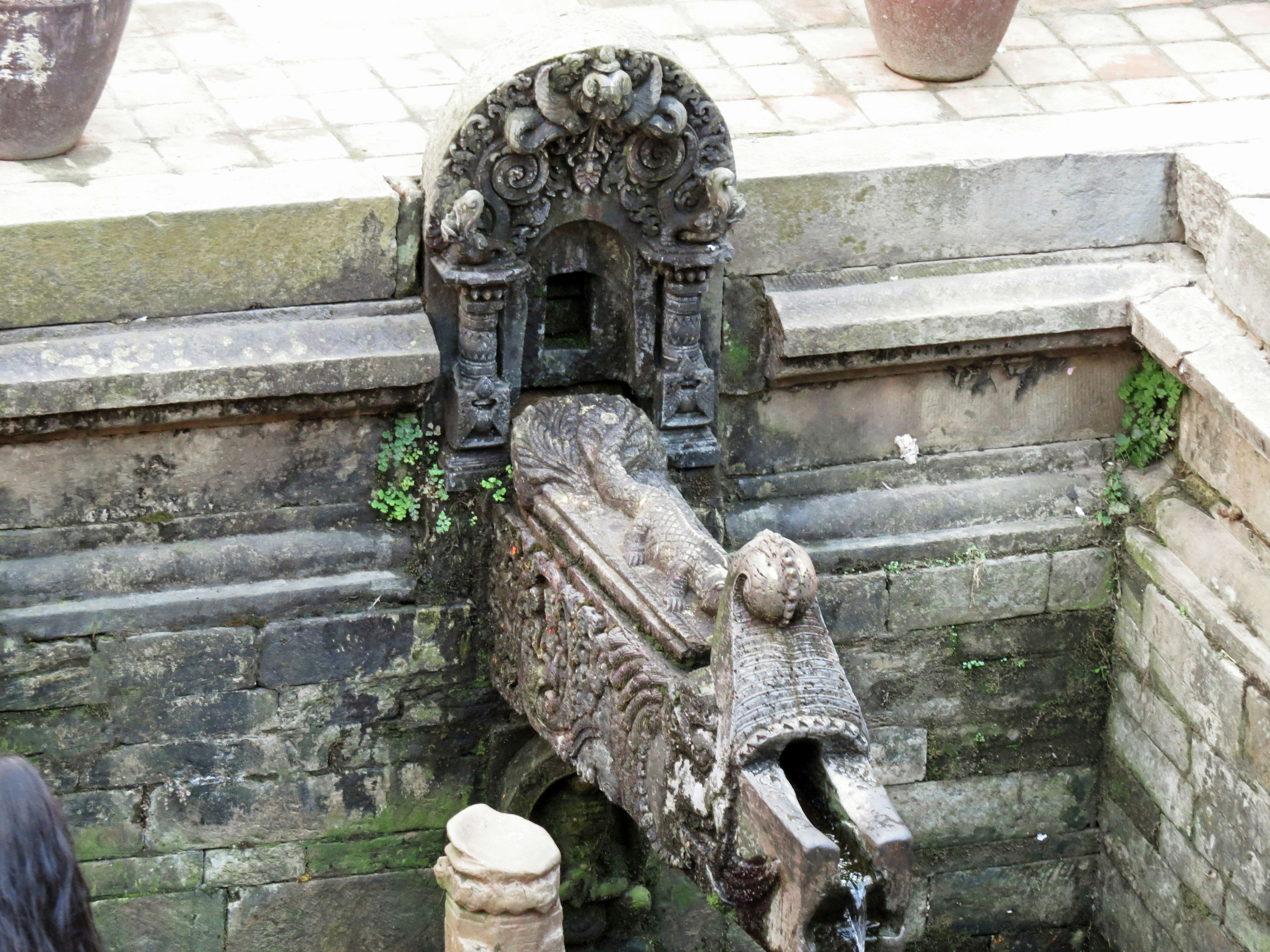 Una fuente de piedra histórica con tallas decorativas en un jardín