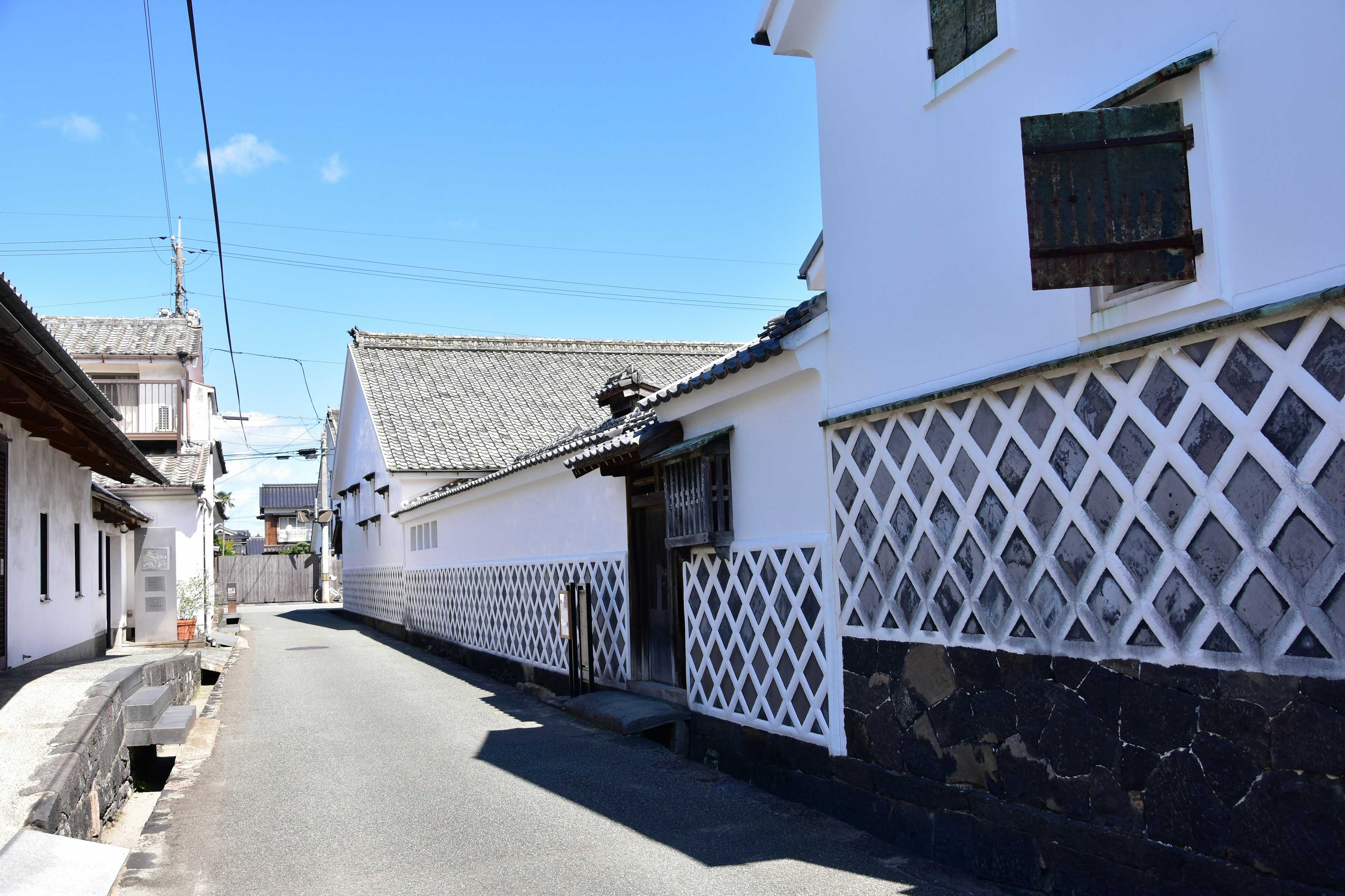 Escena de calle tranquila con paredes blancas y casas con patrón de celosía