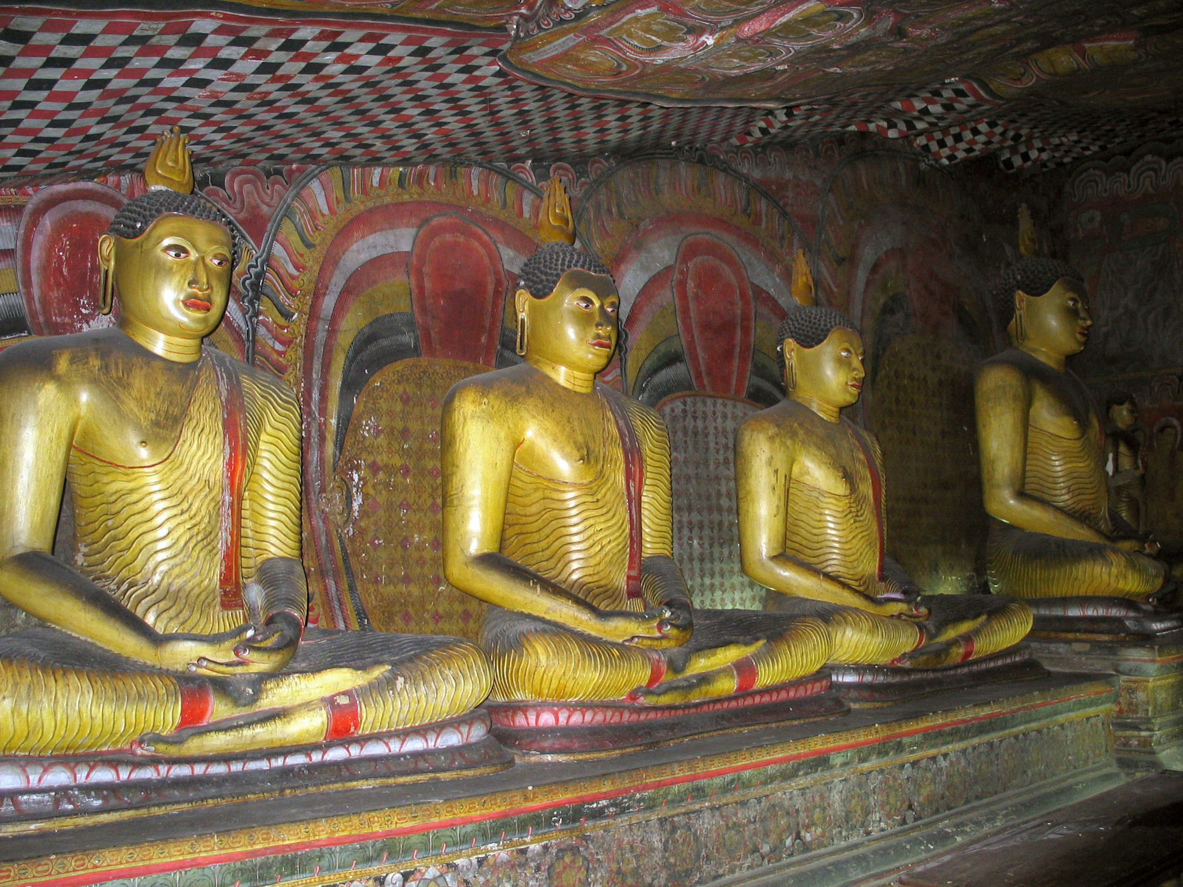 Interior of a cave featuring golden Buddha statues