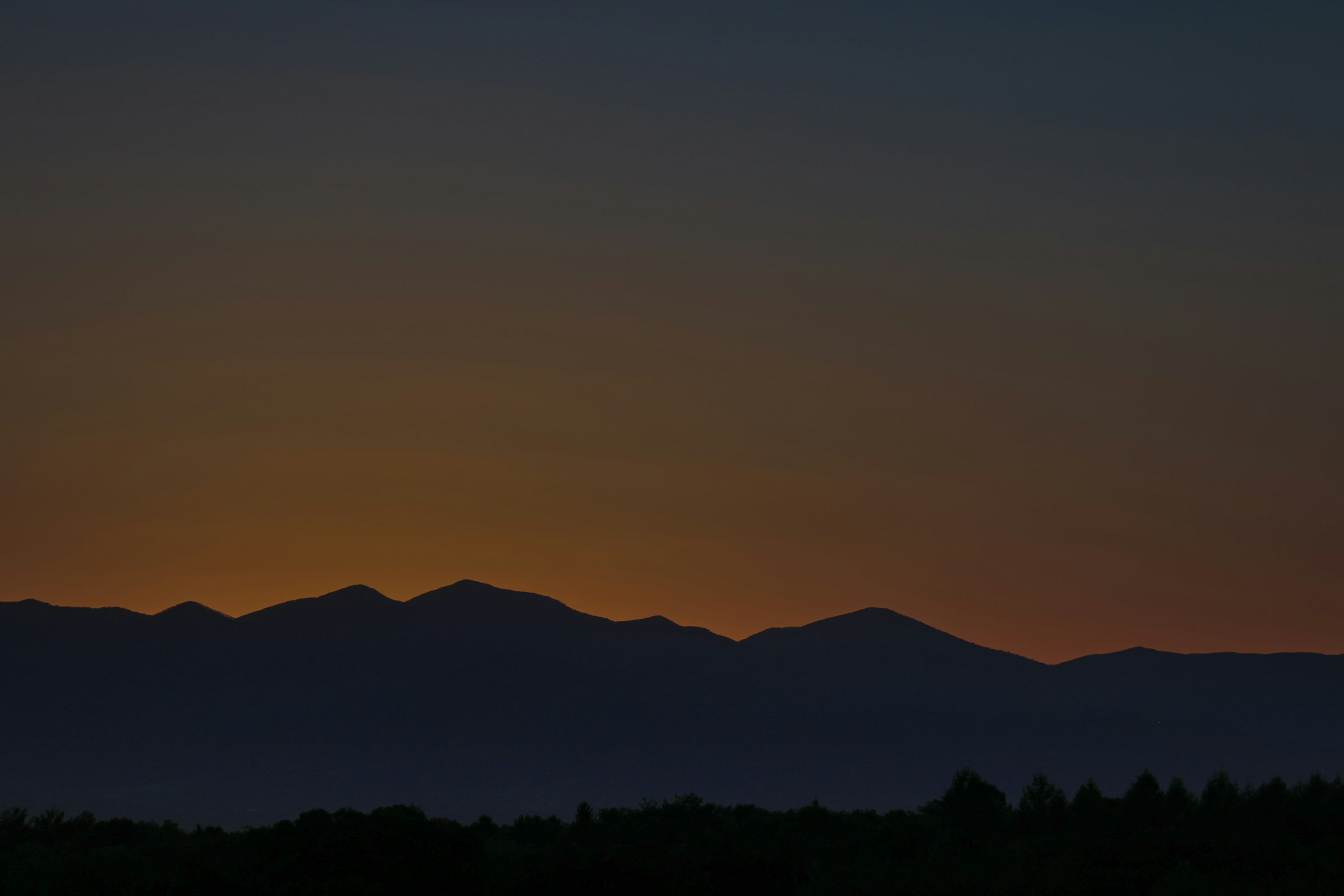 山々のシルエットが夕焼けの空に映える