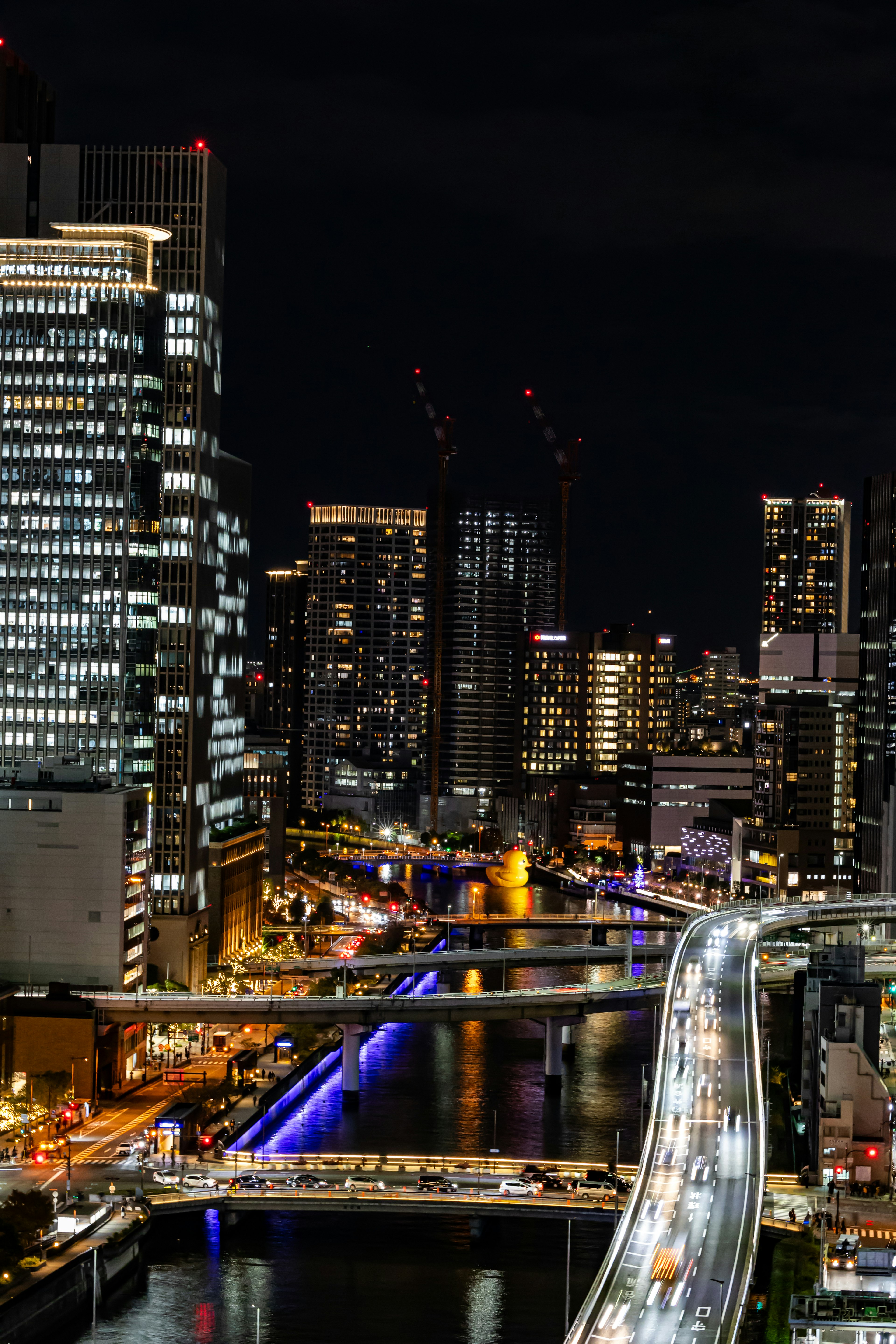 Paisaje urbano nocturno con rascacielos iluminados y luces en el río