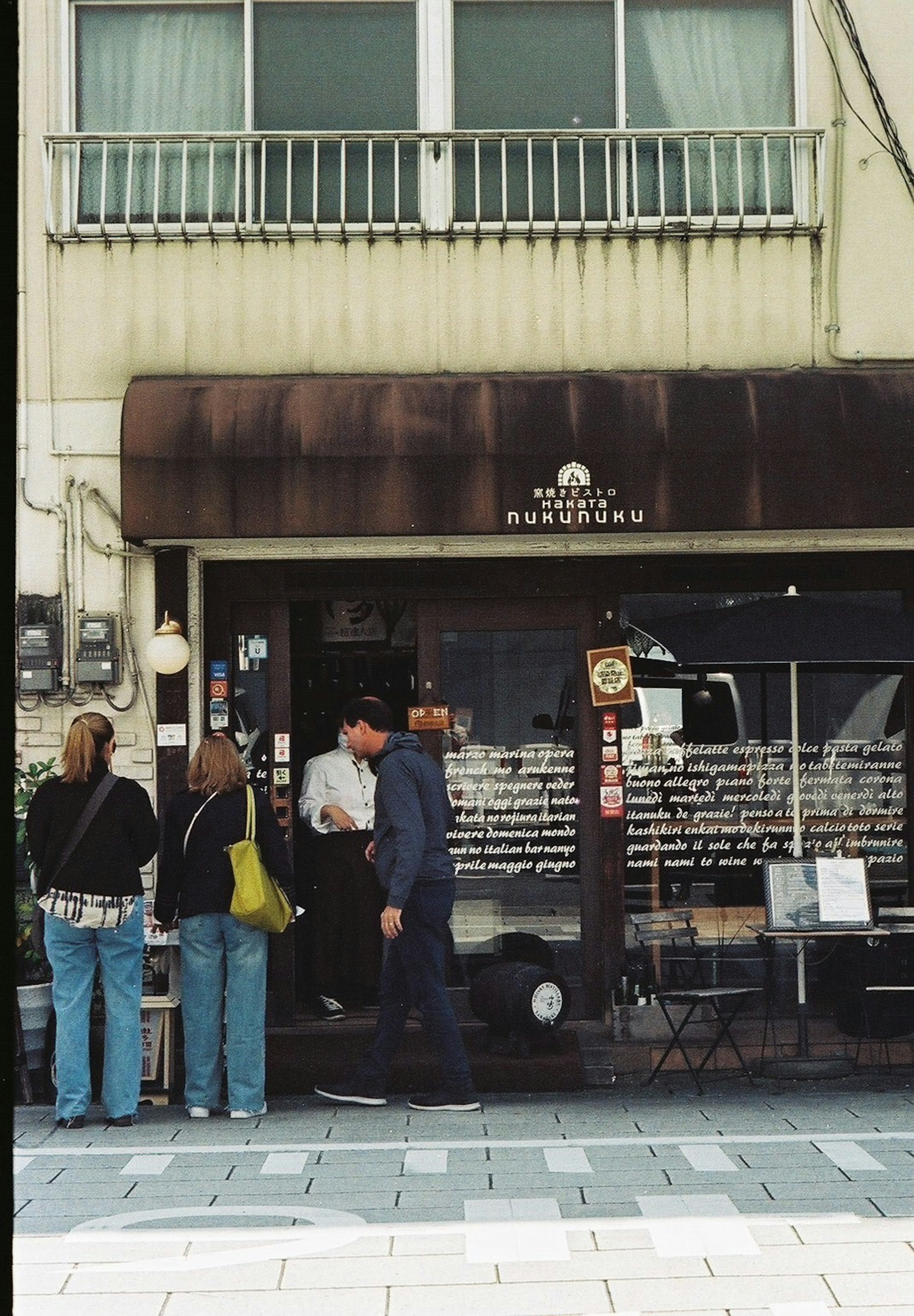 Des gens rassemblés devant un petit café avec une façade rustique