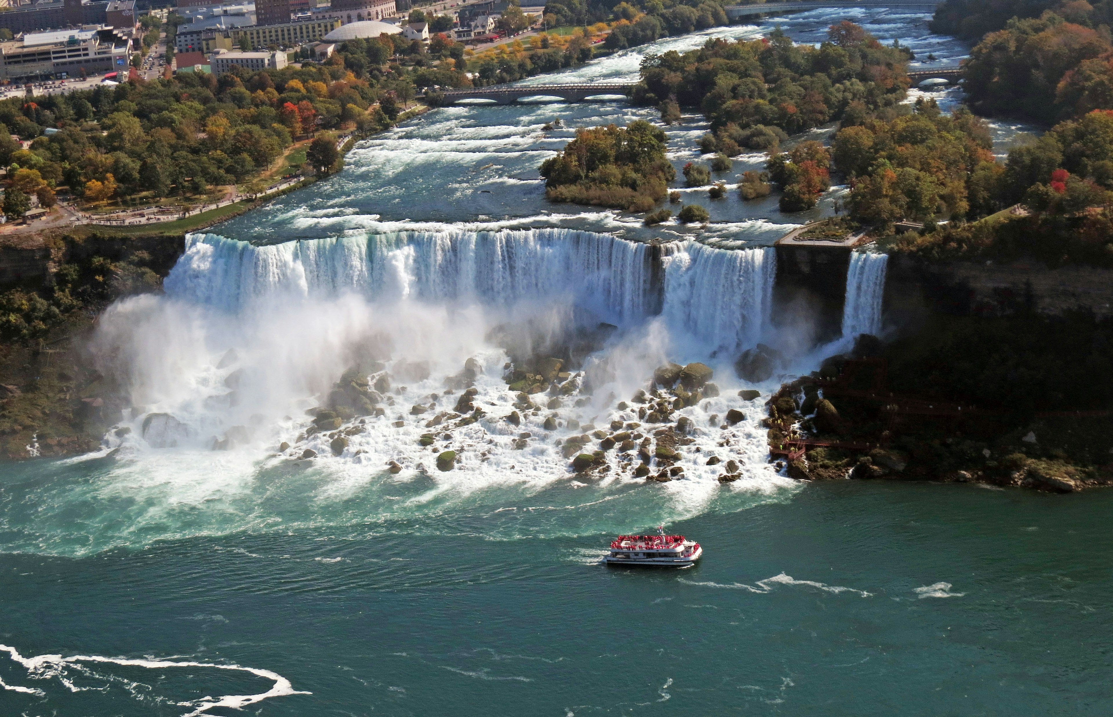 Luftaufnahme der Niagarafälle mit den herabstürzenden Wasserfällen und einem Boot in der Nähe