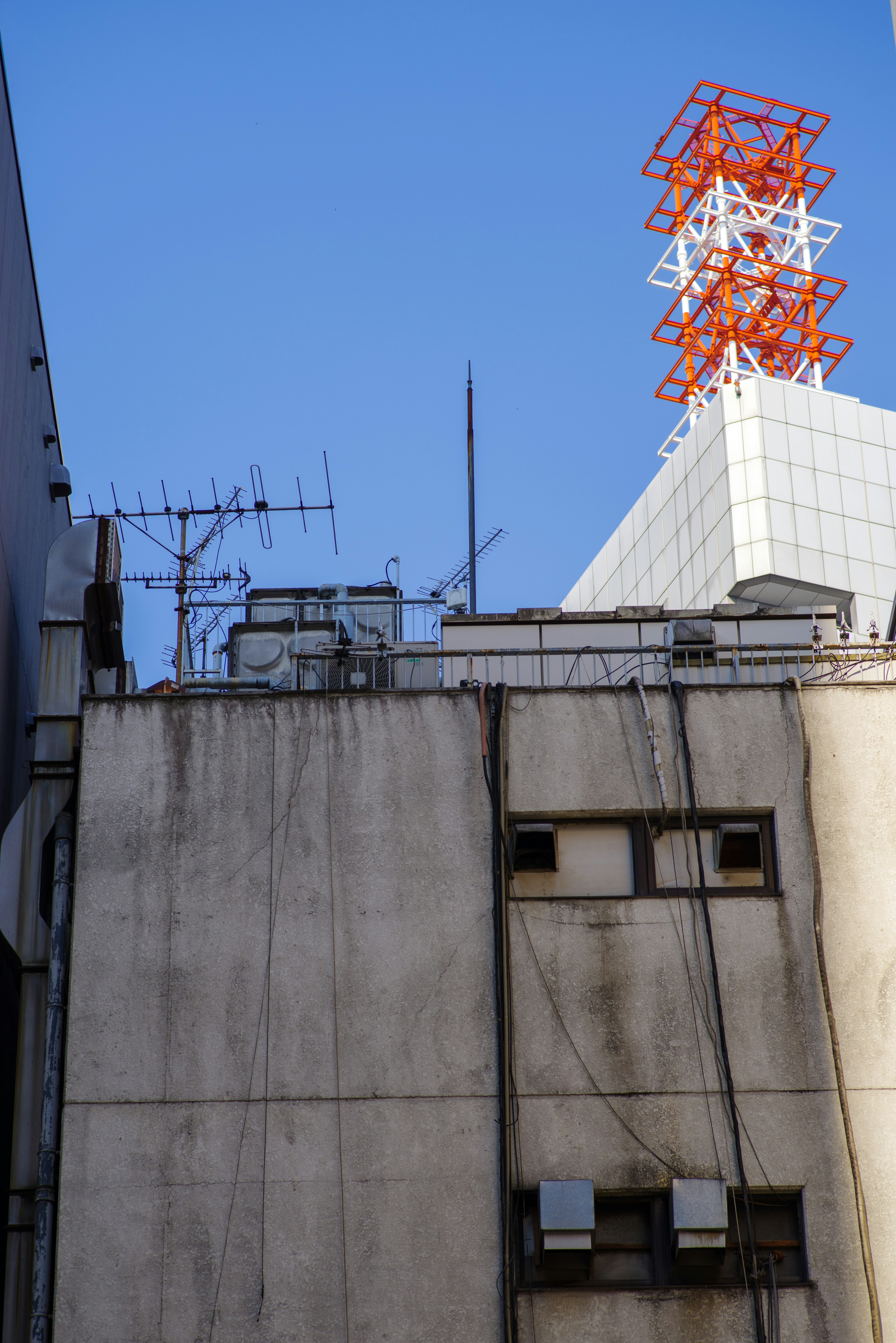 Vista de los techos de edificios con antenas y una torre de comunicación roja