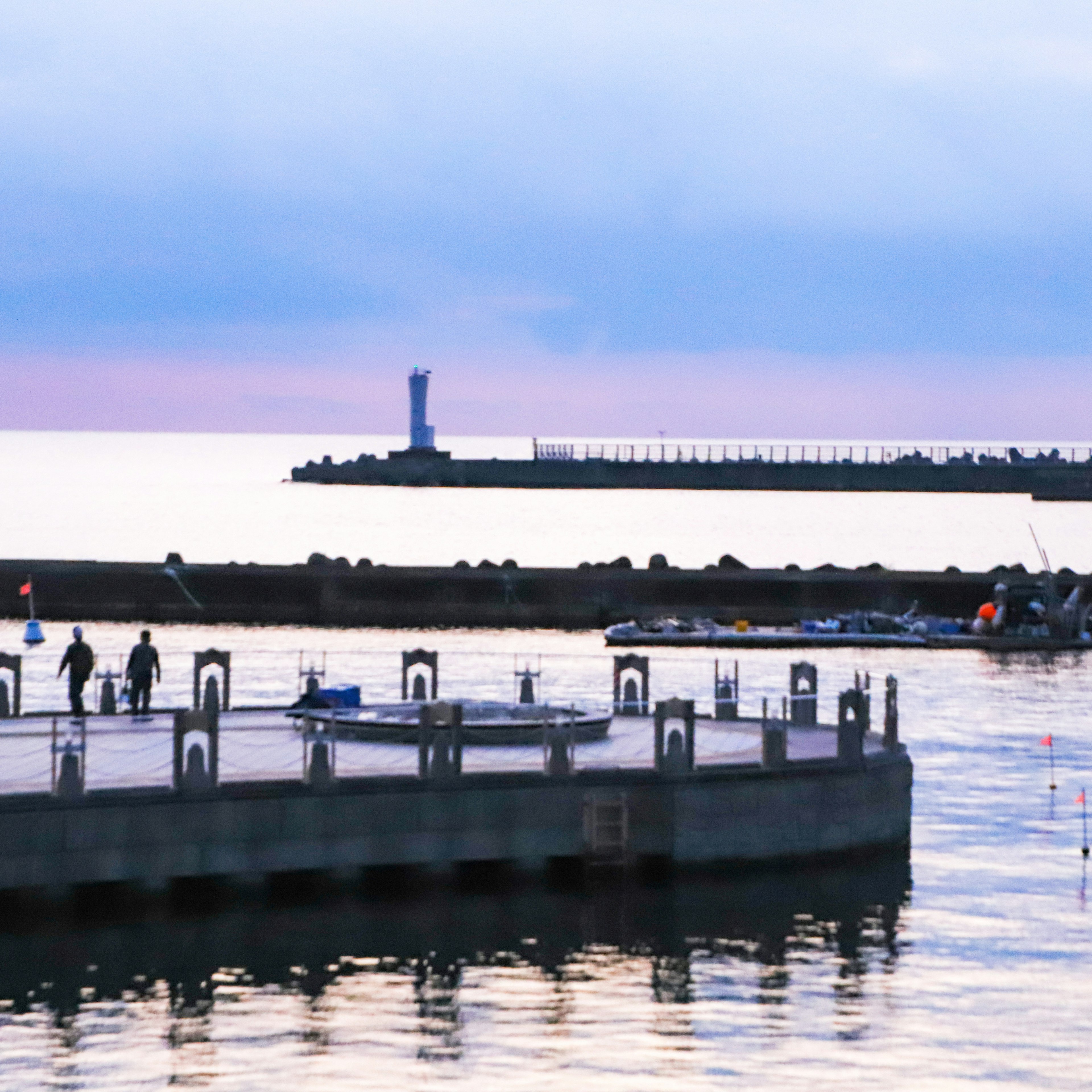 Malerscher Blick auf einen Pier mit Menschen und einem fernen Leuchtturm