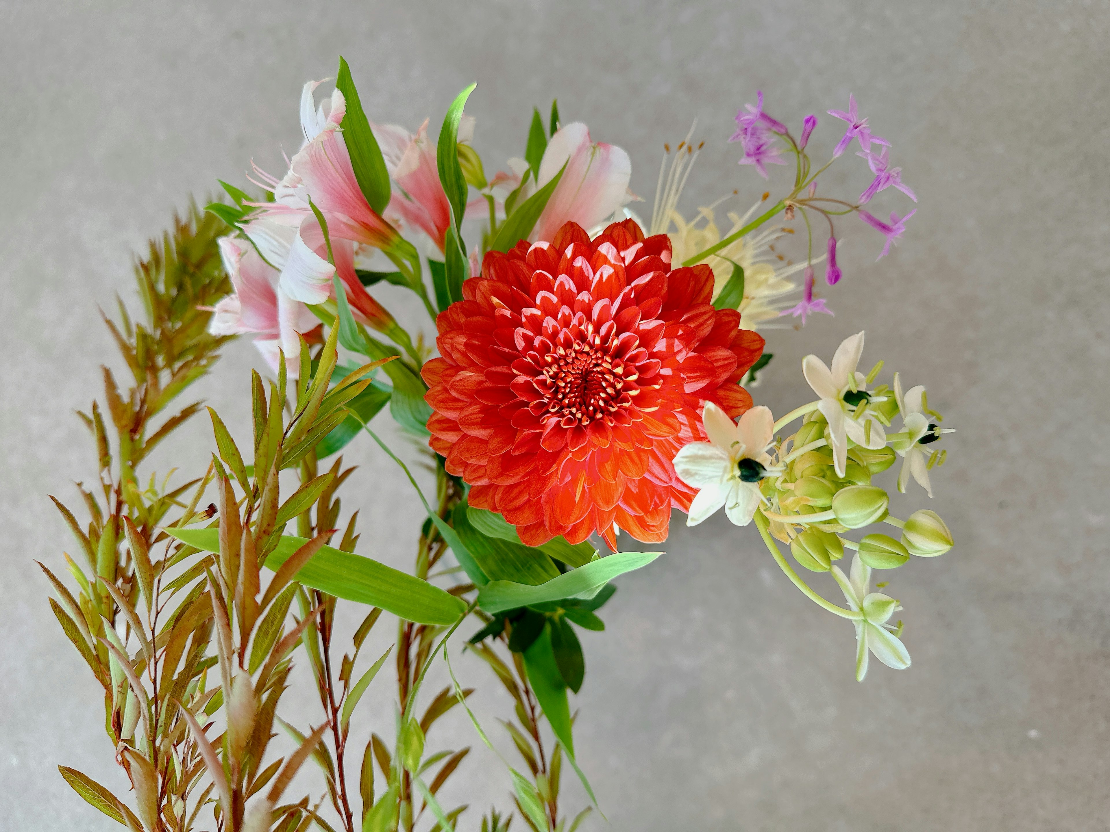 Bouquet mit einer lebhaften orangen Dahlie