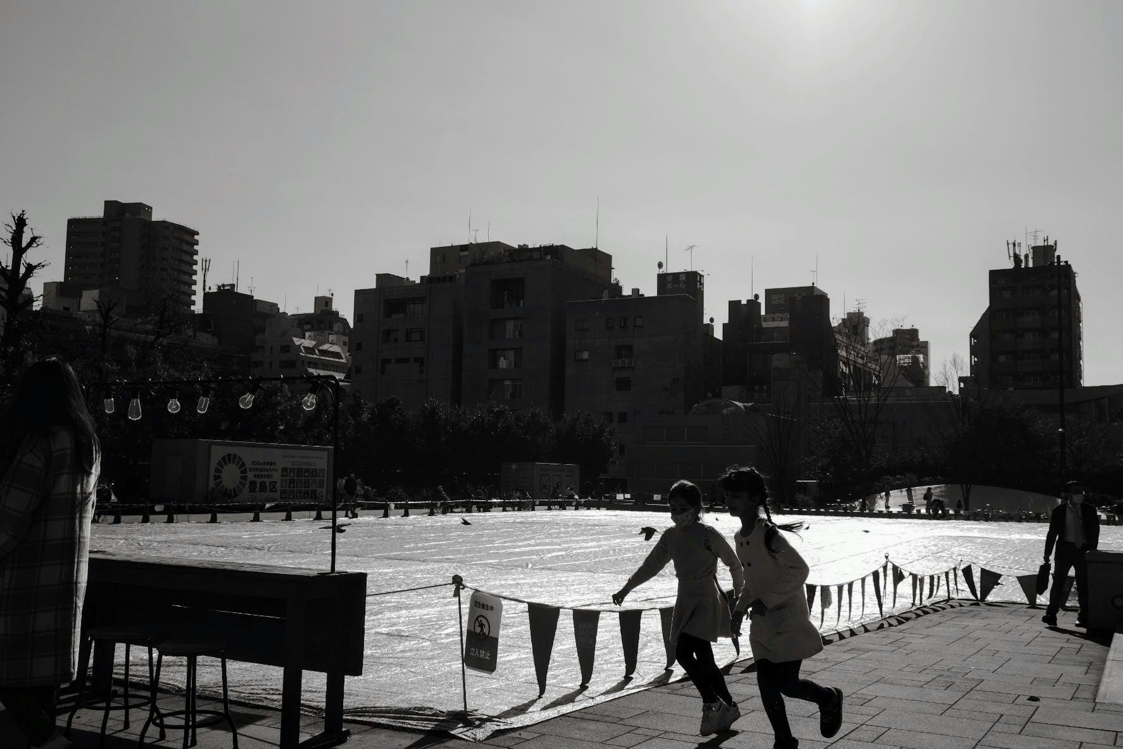 Enfants courant dans une scène de parc urbain en noir et blanc