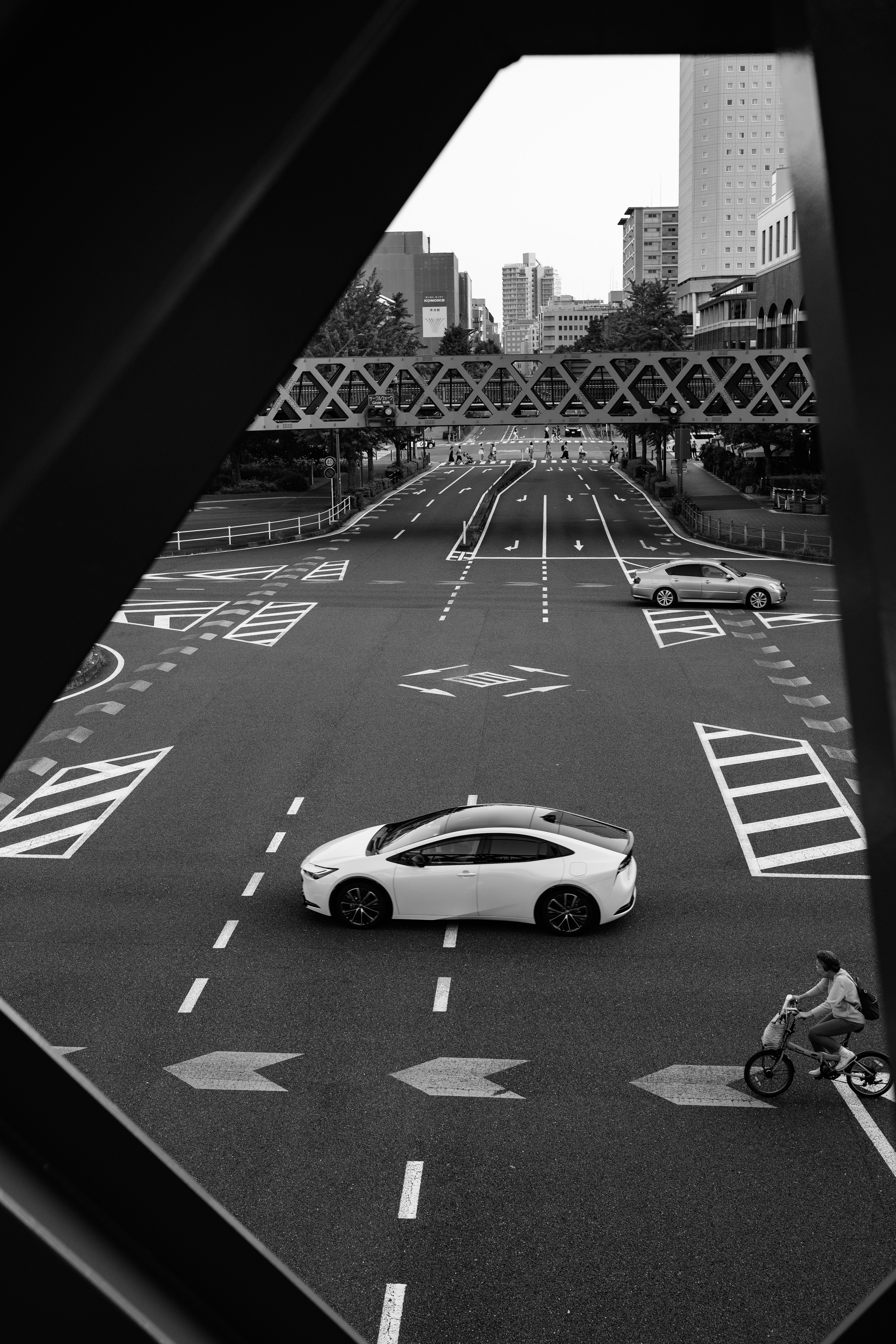 白い車が交差点を渡るモノクロの都市風景