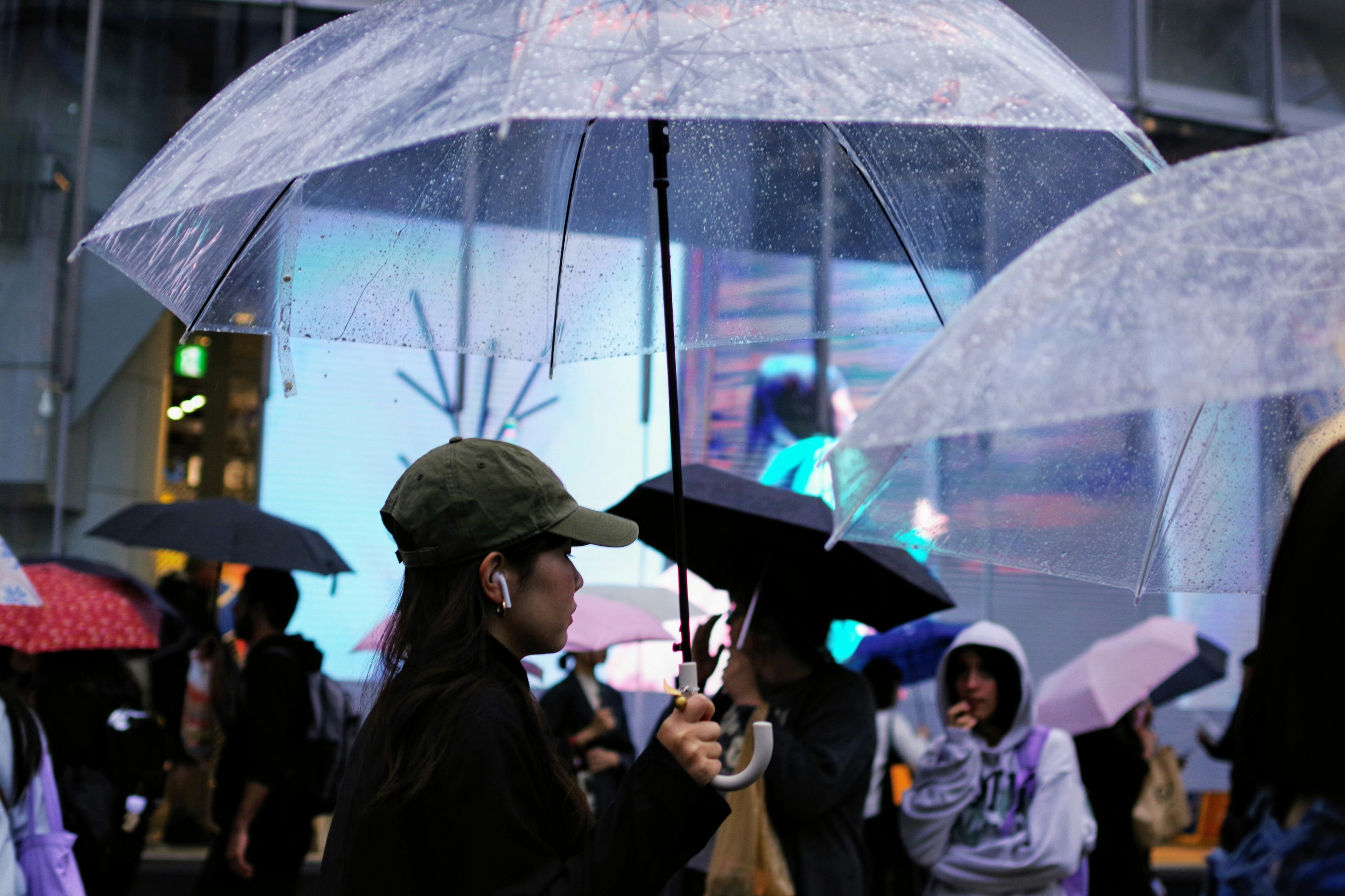 雨の中で傘を持っている人々の群れ 薄暗い背景に明るい広告