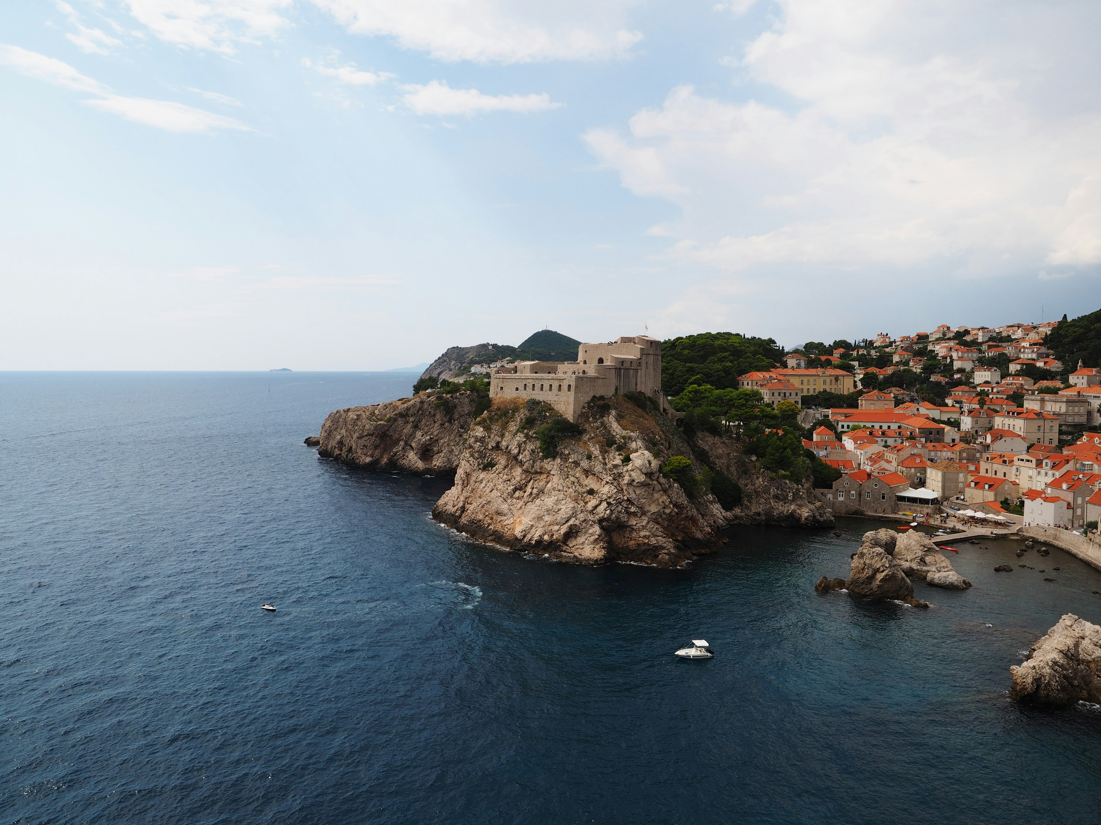 Scenic view of Dubrovnik featuring a coastal fortress and orange-tiled roofs