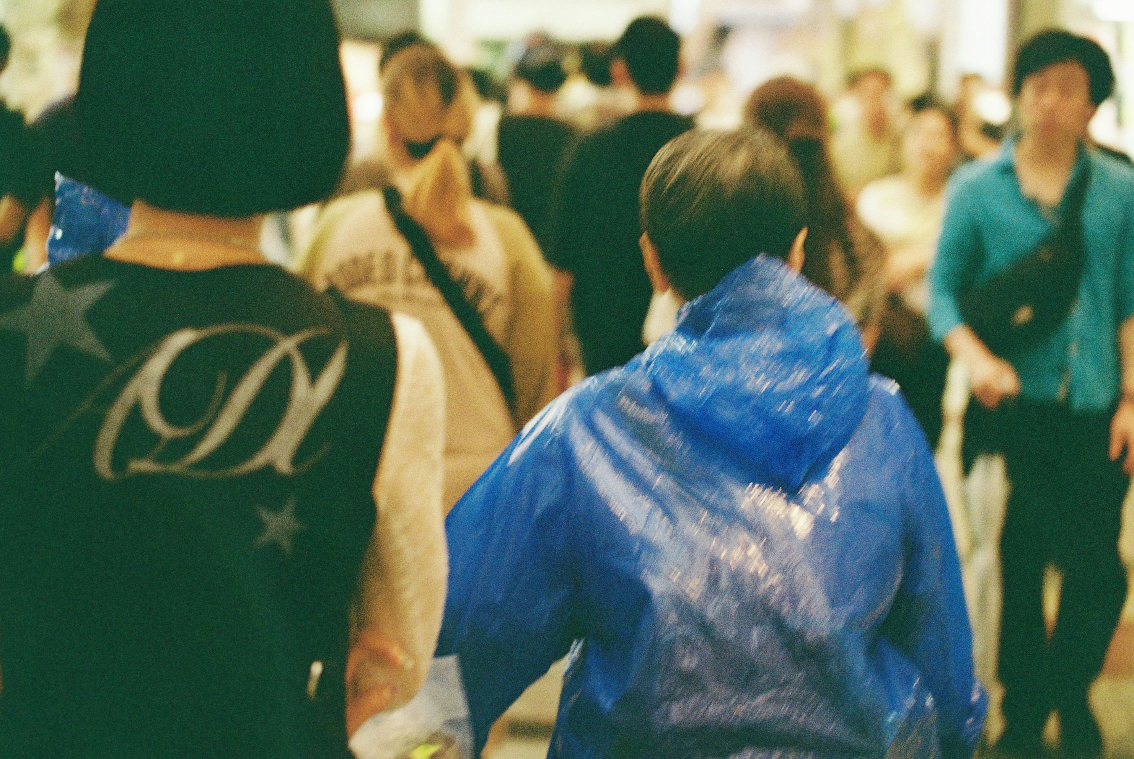 Une personne en imperméable bleu marchant à travers une foule