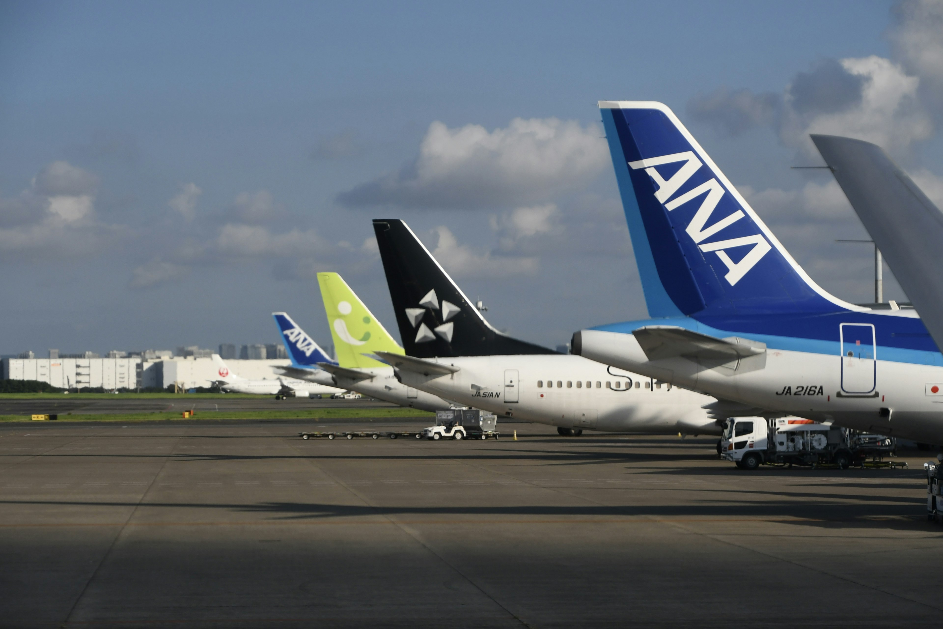 Mehrere Flugzeughecks auf einer Flughafenlandebahn mit einem auffälligen ANA-Logo