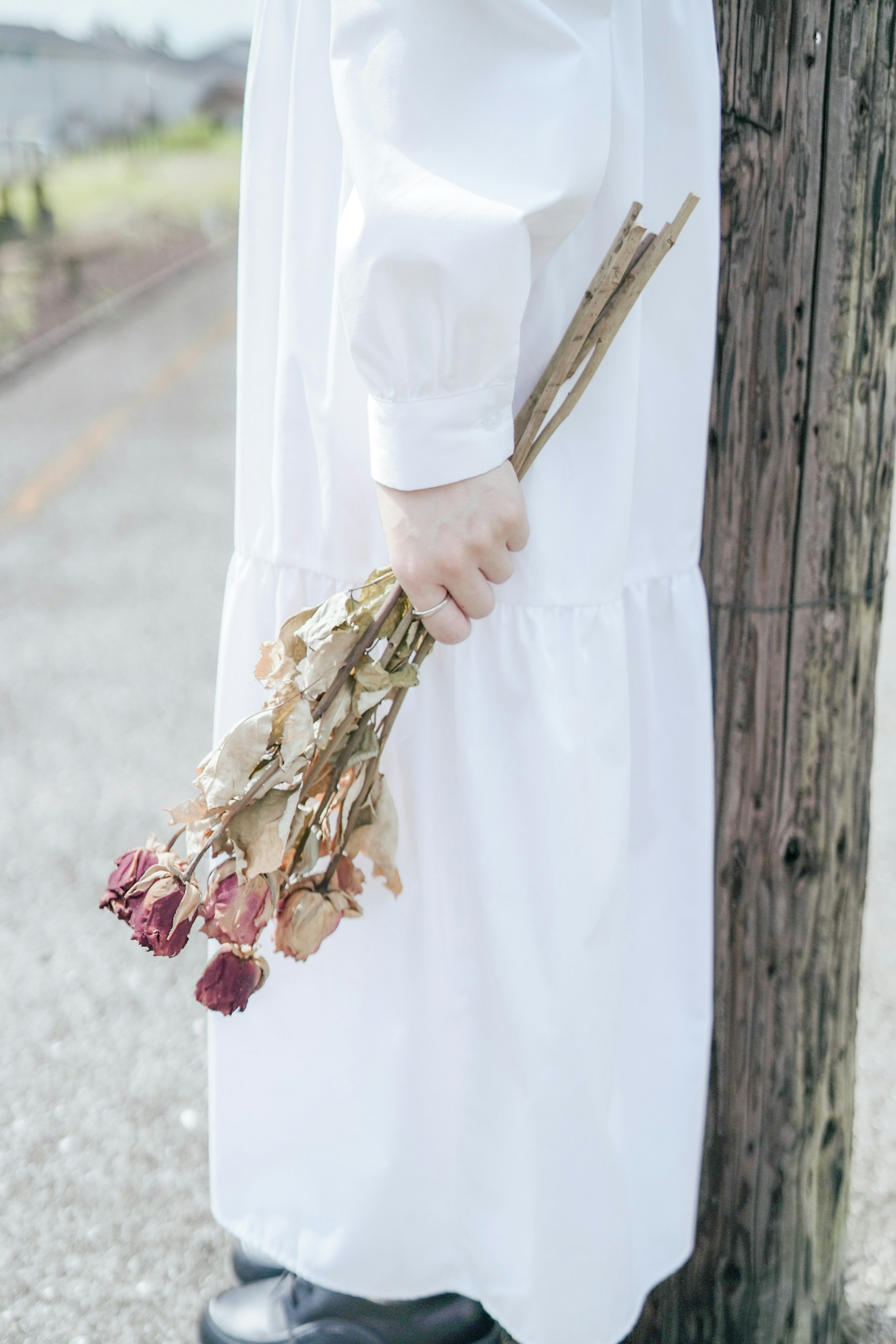 Persona con un vestido blanco sosteniendo un ramo de rosas secas