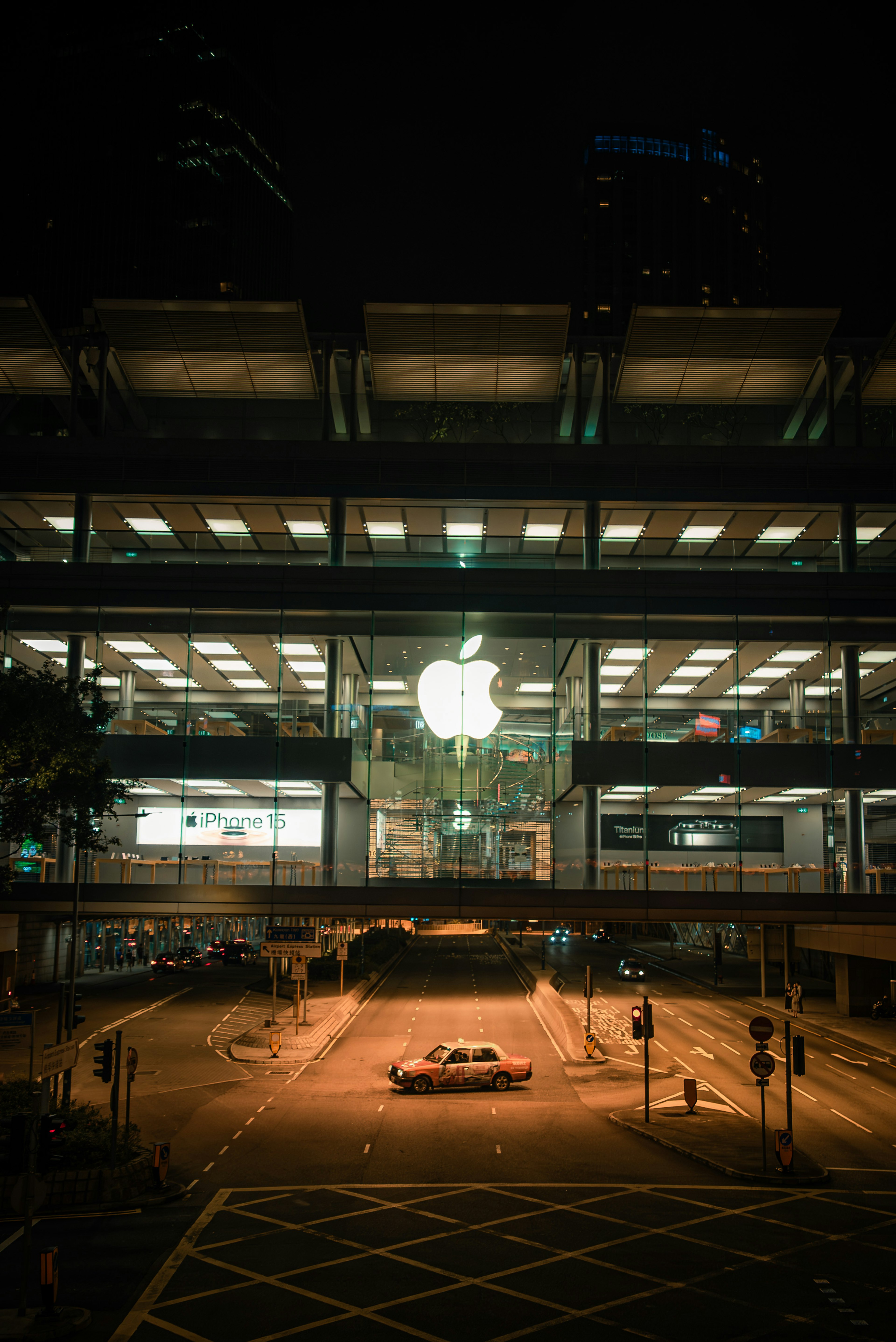 Bright Apple Store logo illuminated at night with glass facade