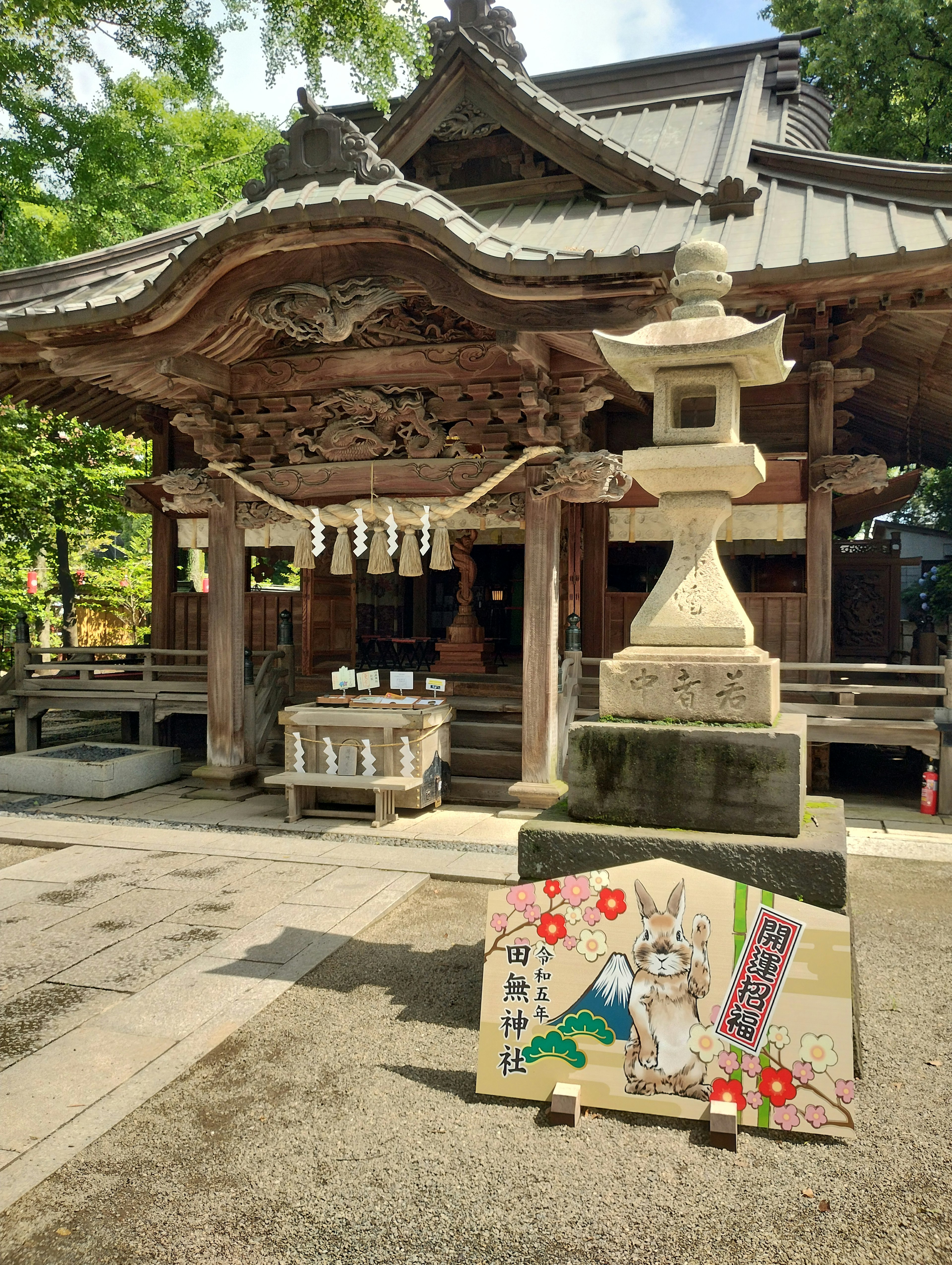 传统神社建筑，旁边有石灯笼和兔子插图的标志