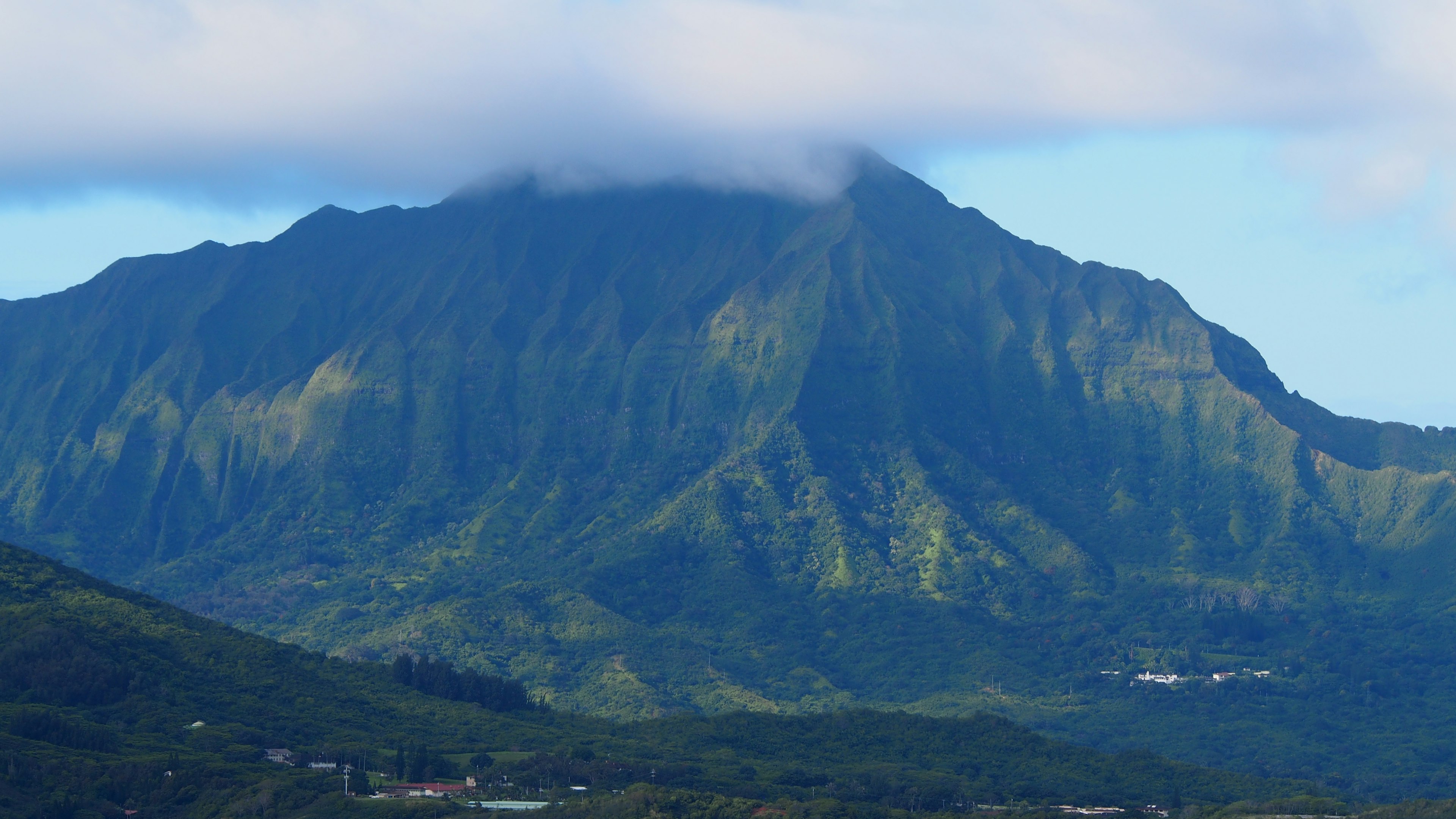 Gunung hijau dengan awan menutupi puncaknya