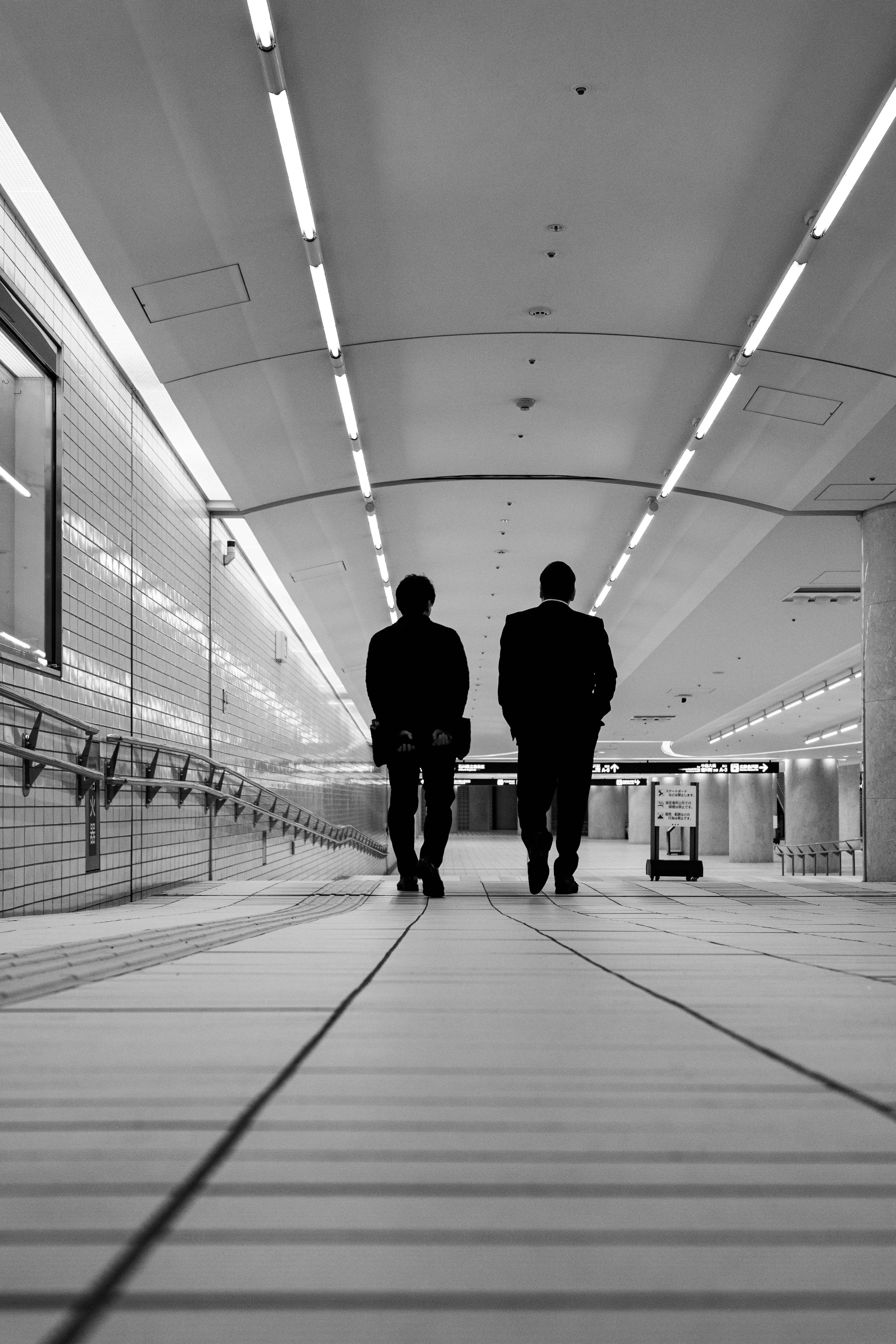 Two businessmen walking in a black and white underground passage