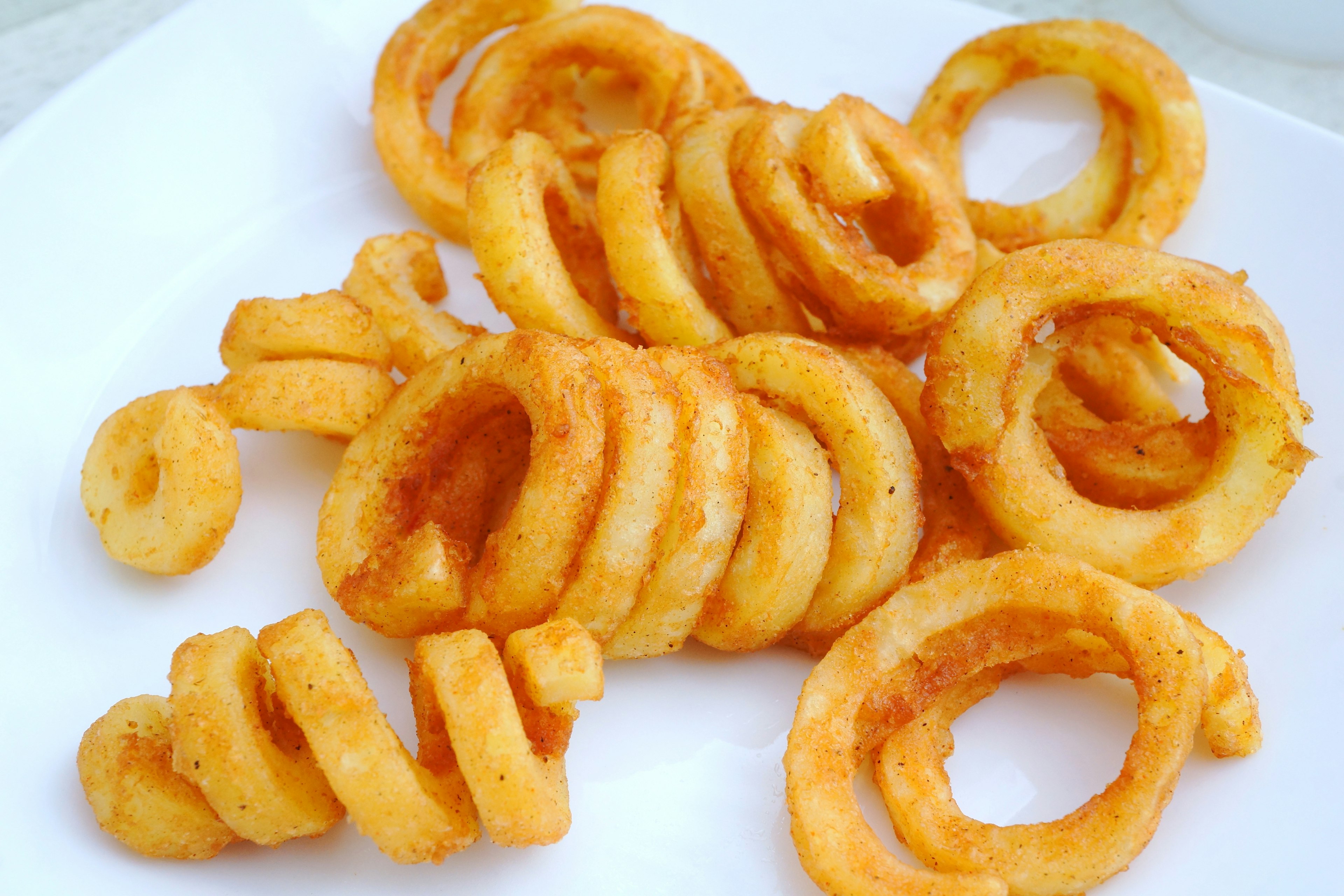 Curly fried potatoes arranged on a white plate