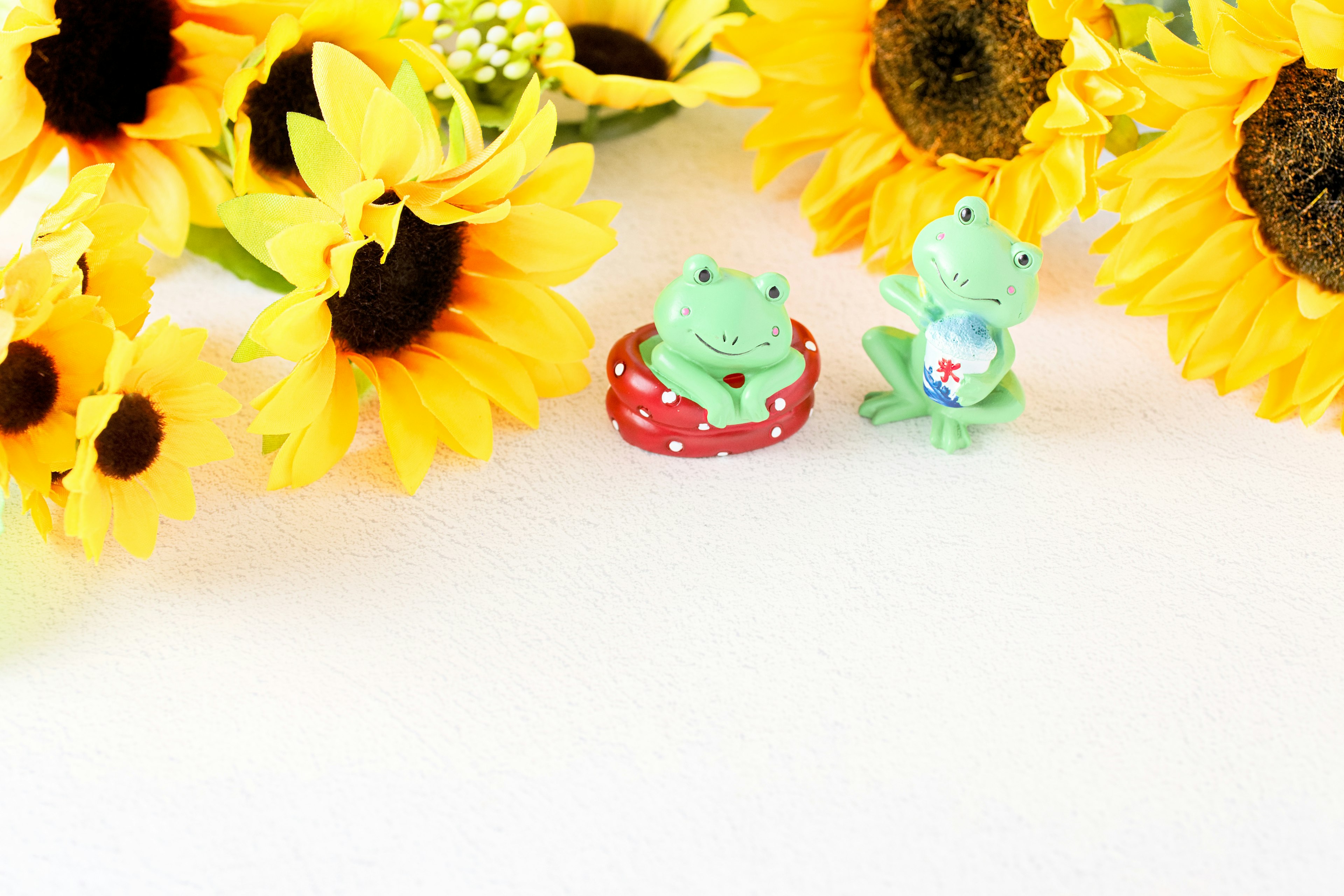 Two frog figurines surrounded by bright yellow sunflowers