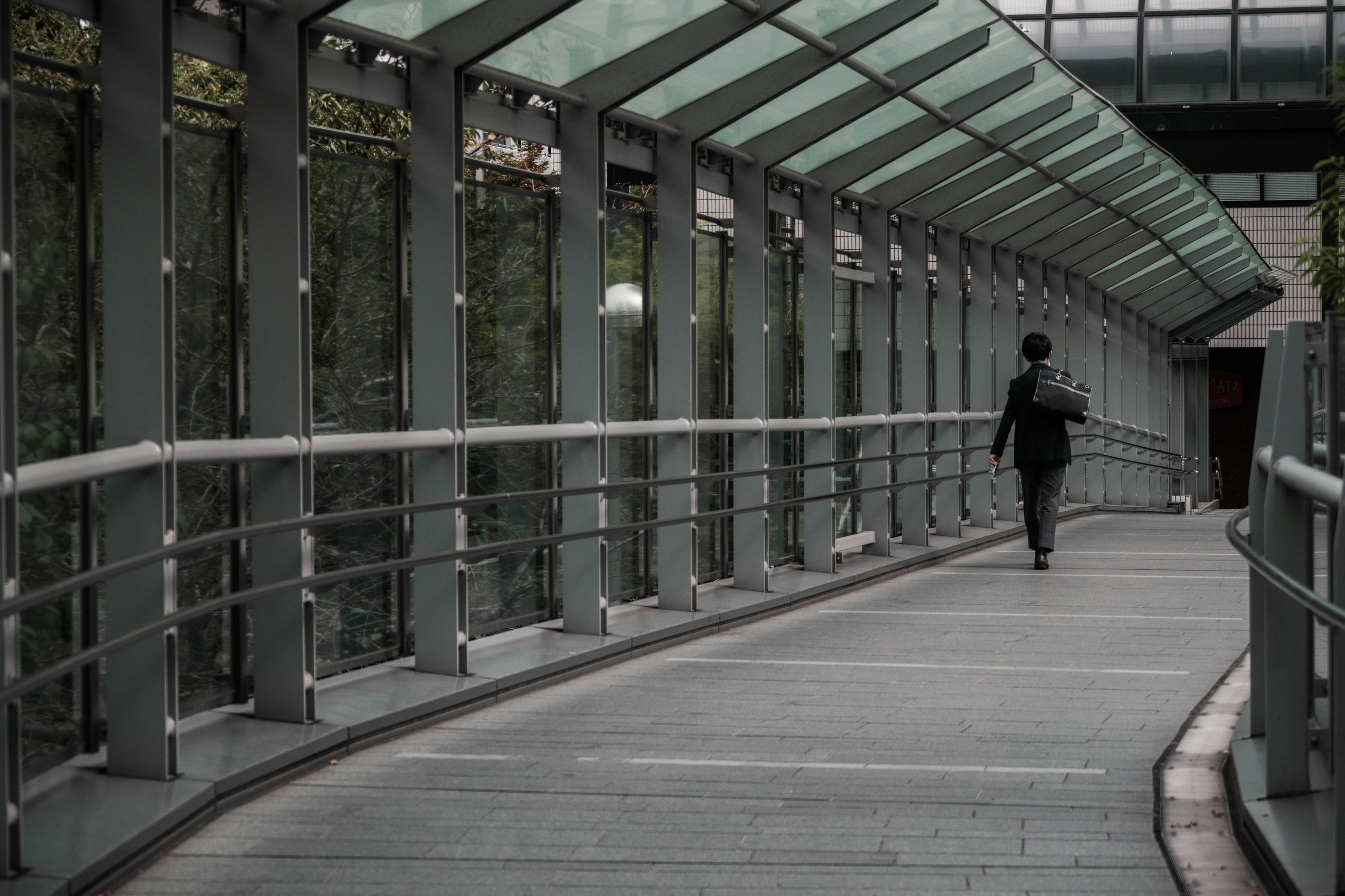 Hombre de negocios caminando bajo un pasillo de vidrio