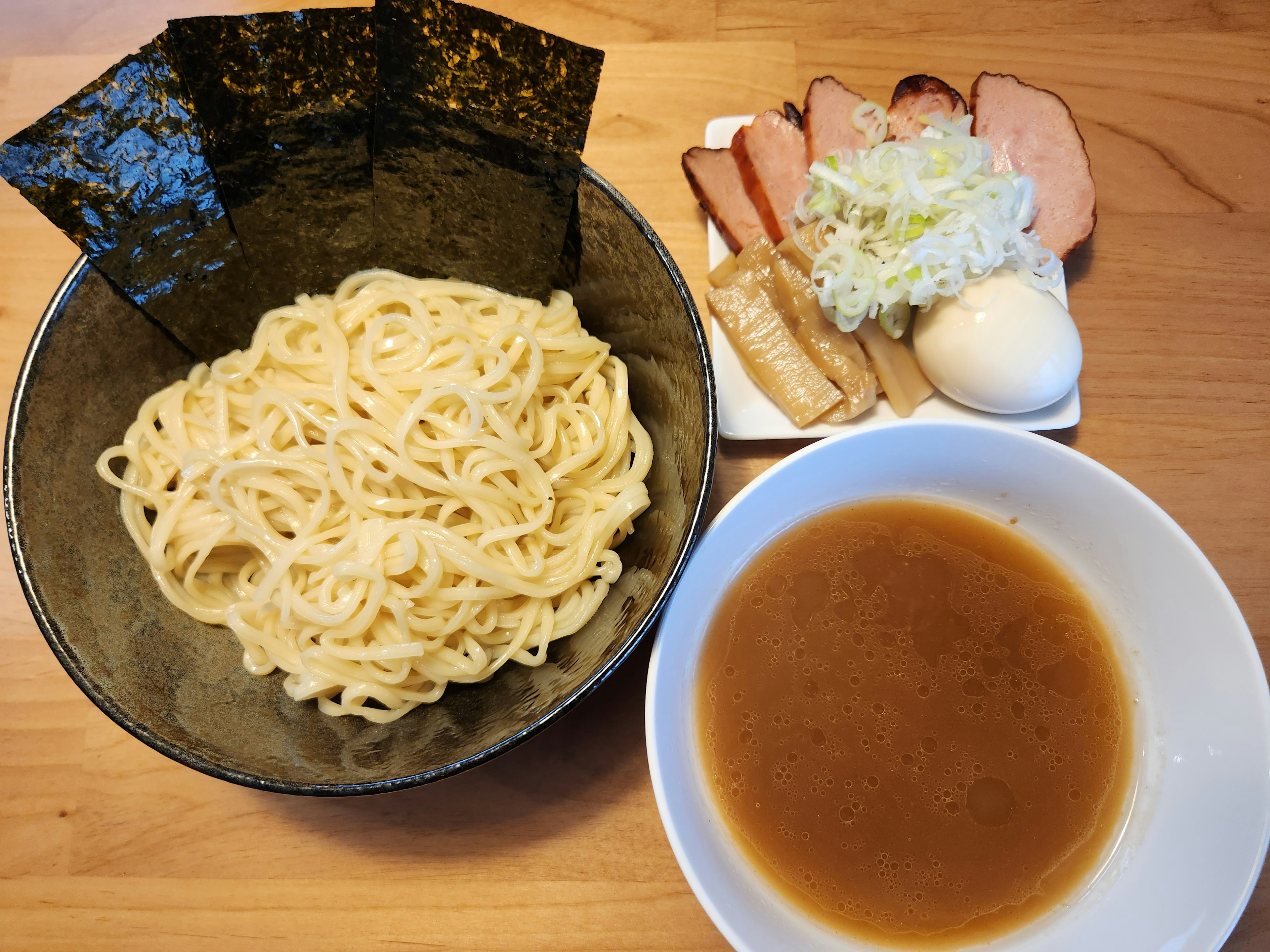 Tsukemen giapponese con contorni serviti su un tavolo di legno