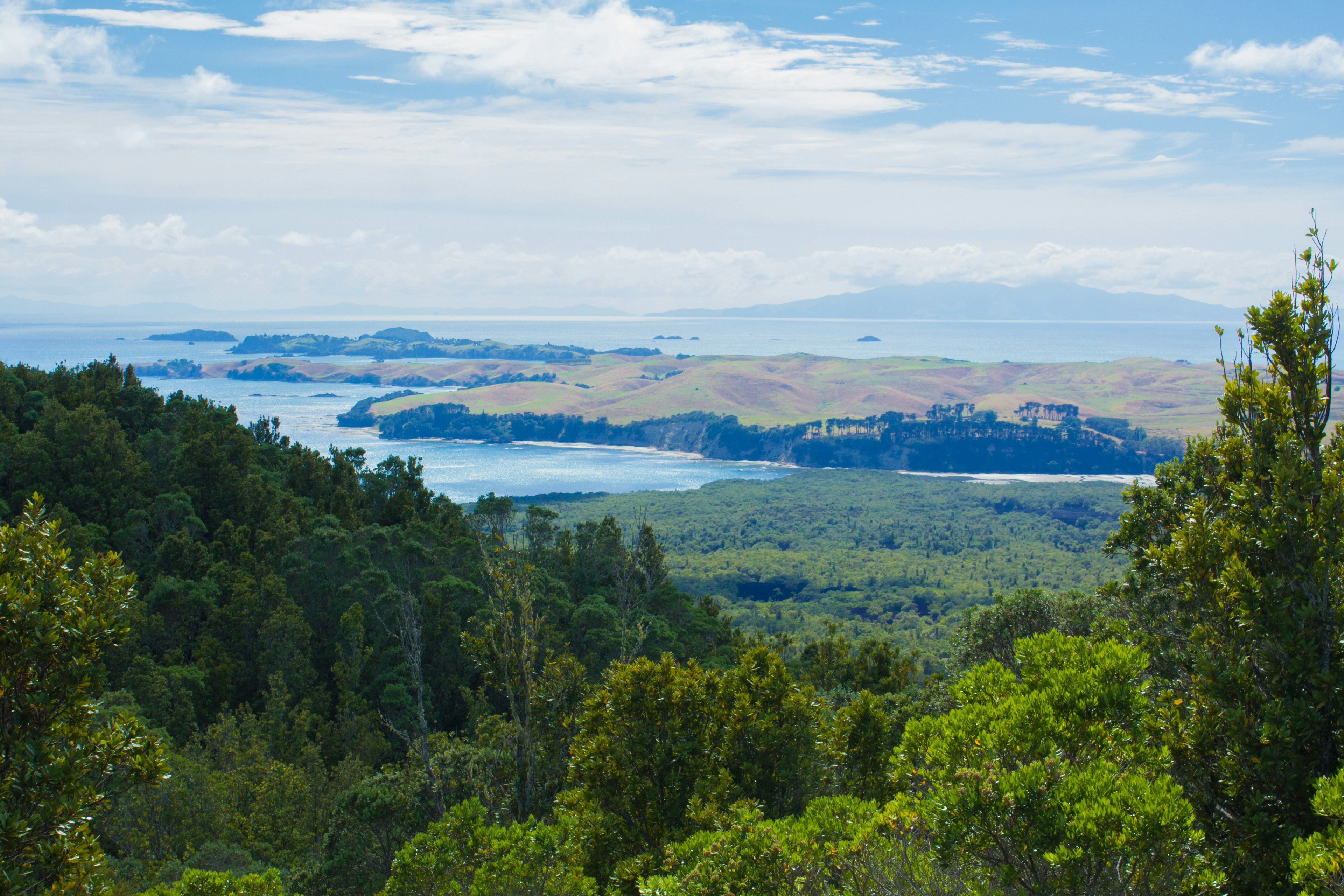 Scenic view of green hills and blue waters under a bright sky