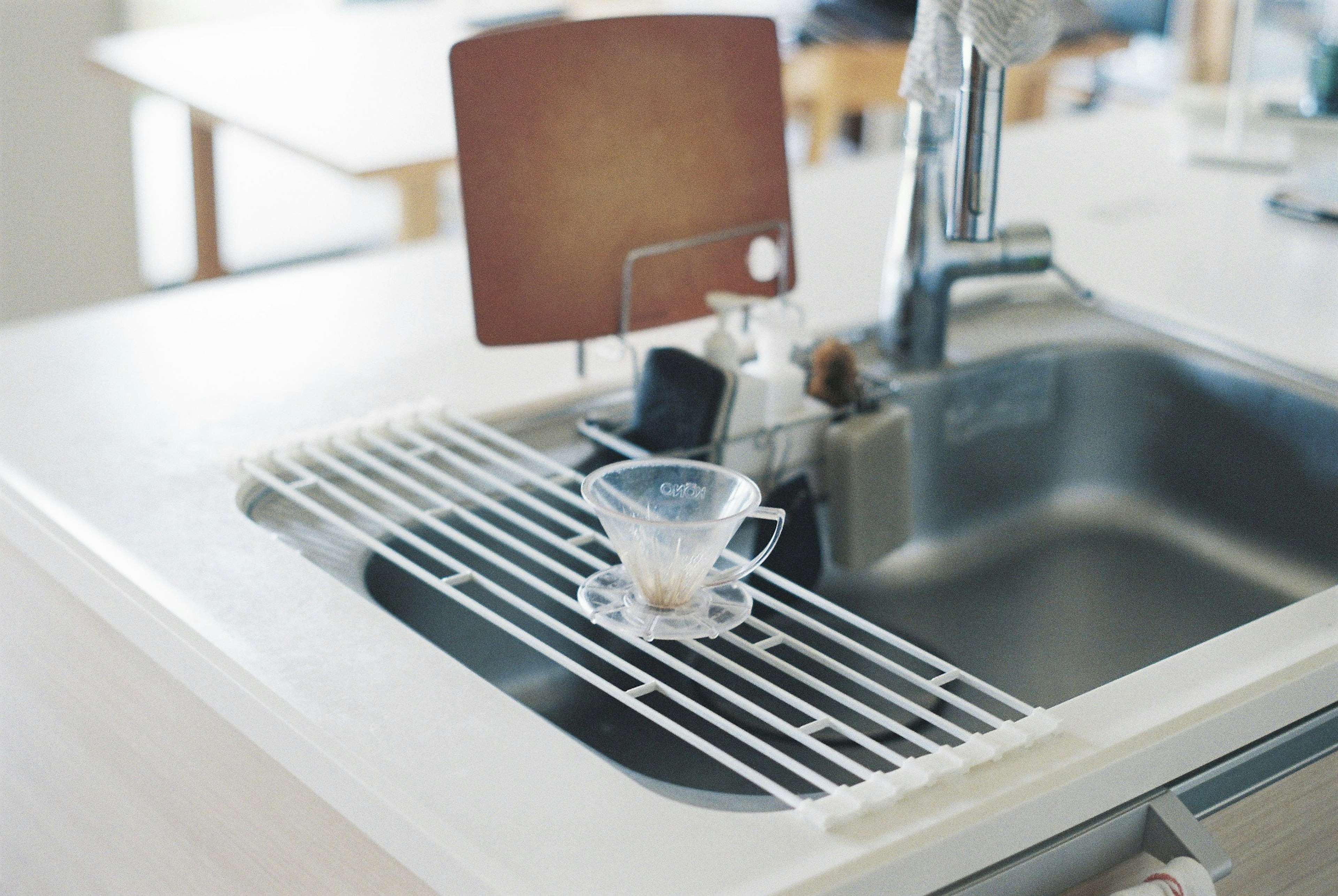 Coffee dripper placed on a simple kitchen sink with a wooden board