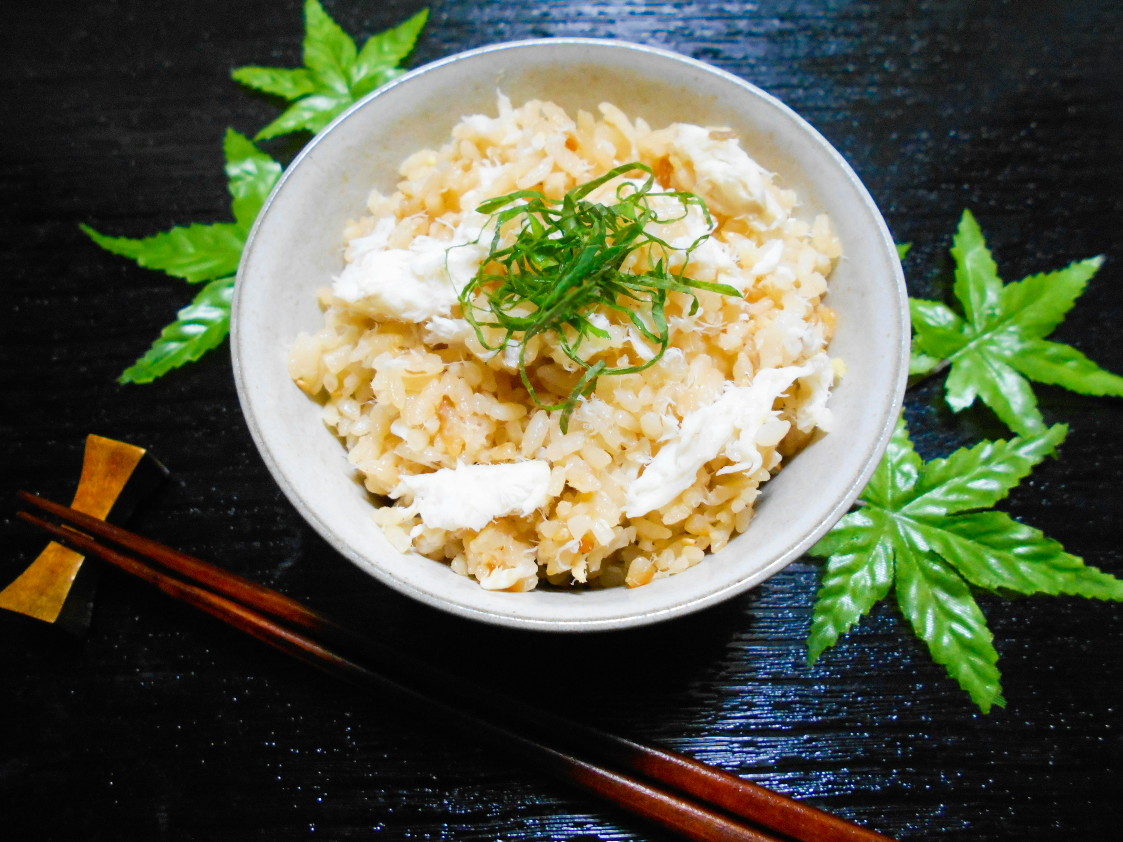 Bol de riz garni d'oignons verts sur une table en bois sombre