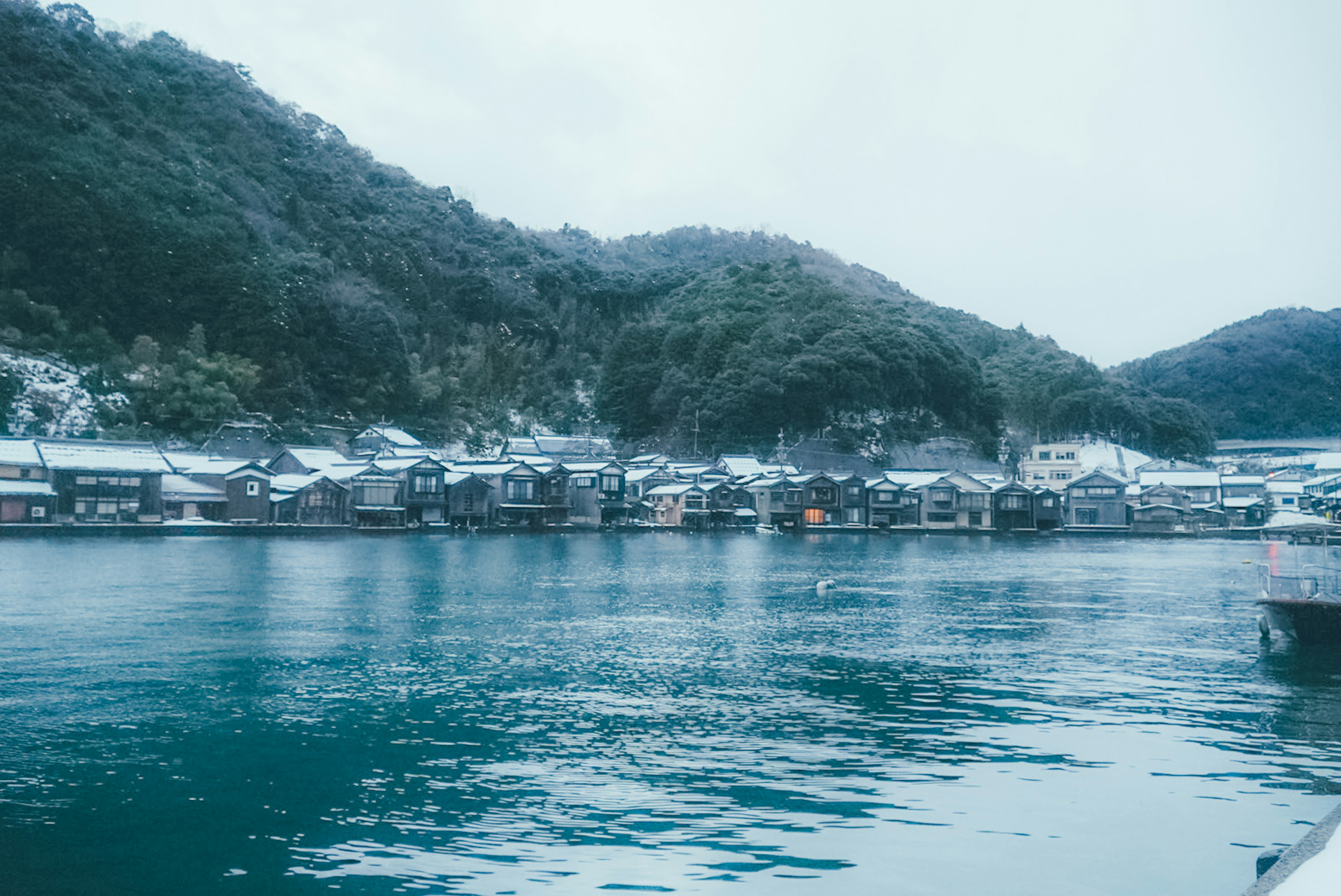 静かな海と山に囲まれた小さな港町の風景