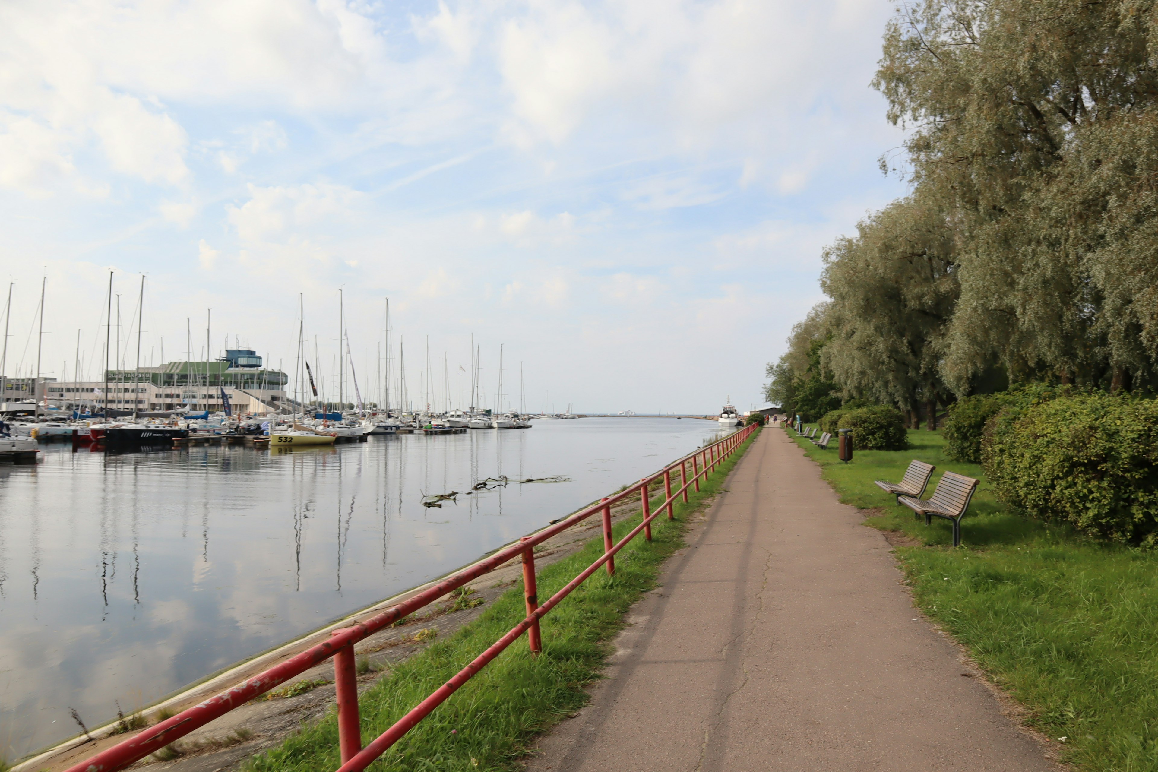 Scenic waterfront walkway with greenery and moored boats