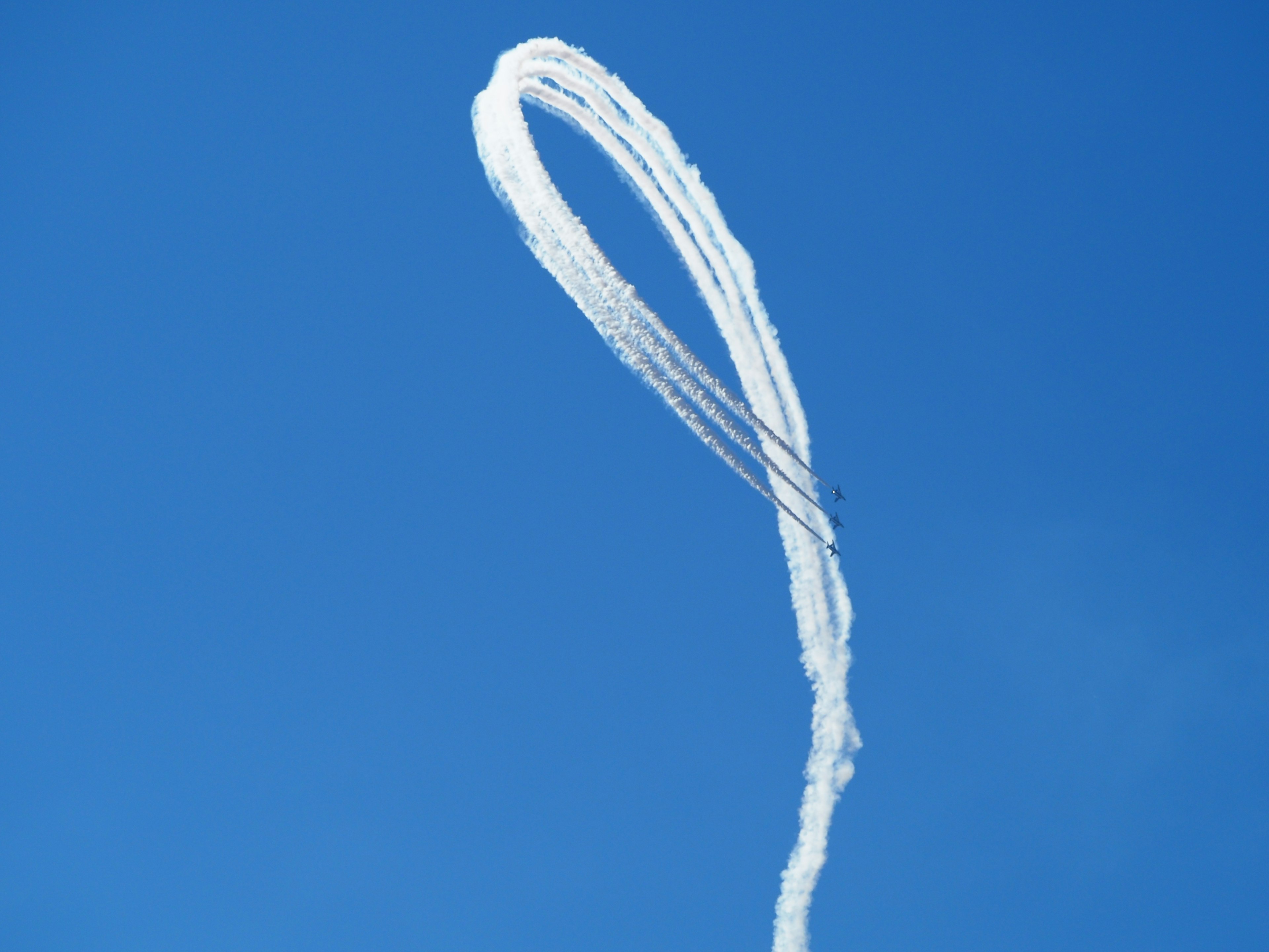 A striking image of white smoke trails against a blue sky